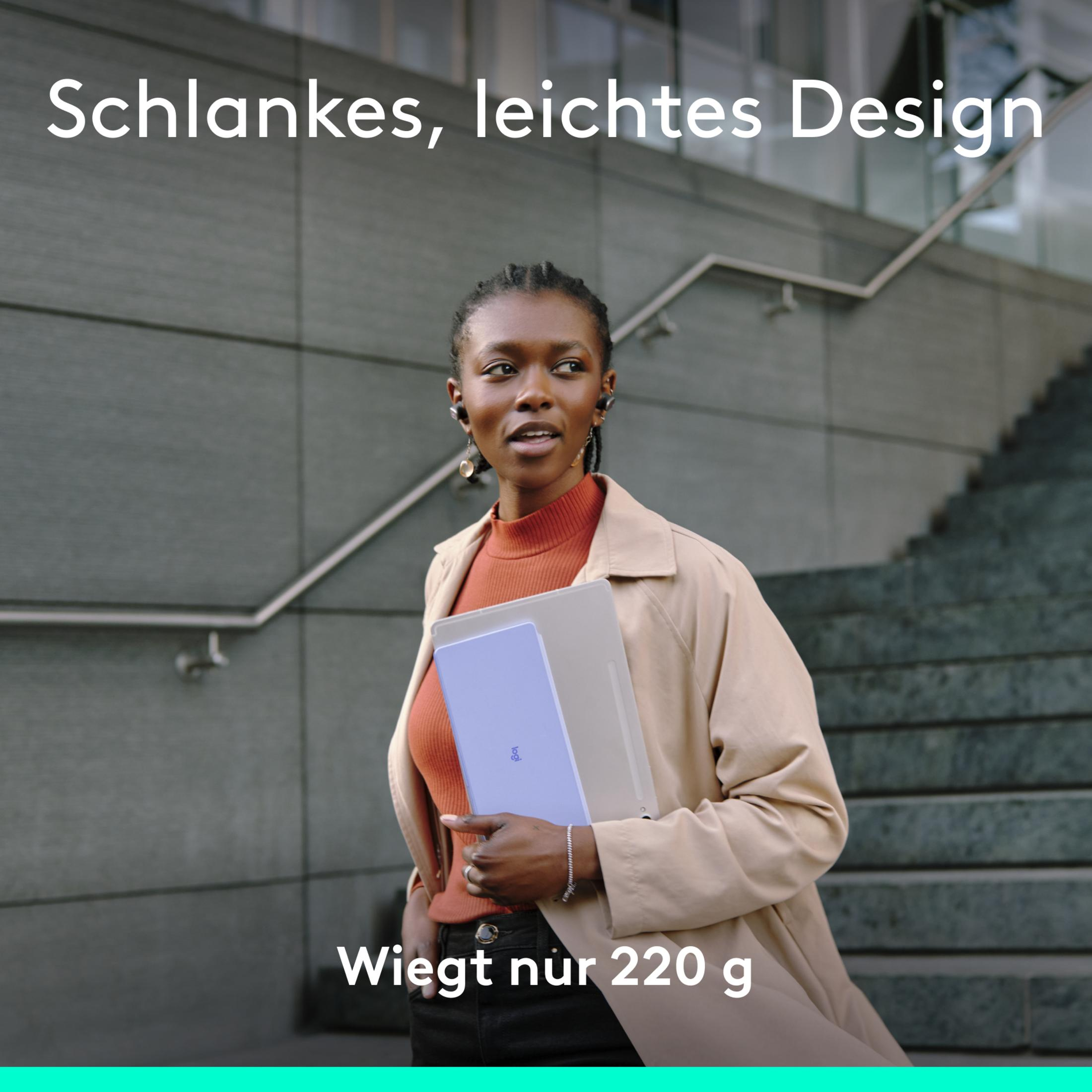Frau hält Laptop und Tablet, steht in der Nähe eines Gebäudes mit Treppe.