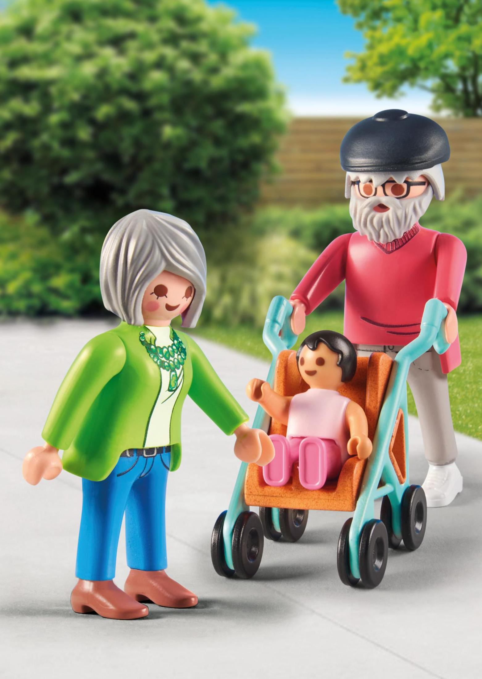 Playmobil-Figuren: eine Frau, ein Mann und ein Kind im Kinderwagen. Sie gehen auf einem Bürgersteig.