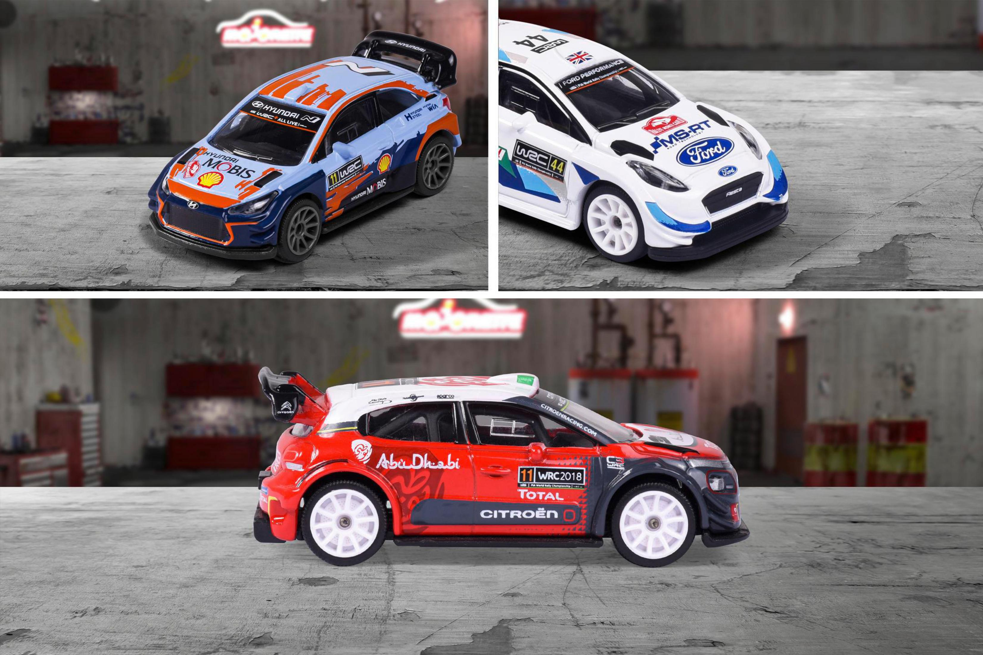 Drei Spielzeug-Rallyeautos auf einer Oberfläche mit lackiertem Garagenhintergrund.