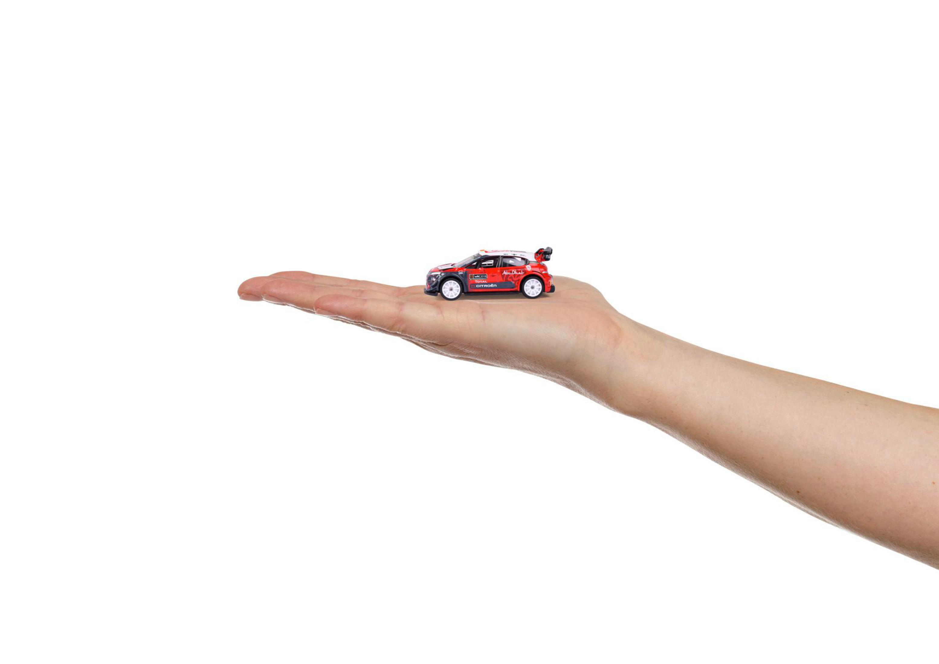 Ein Miniatur-Rotauto wird in der Handfläche gehalten, vor weißem Hintergrund.