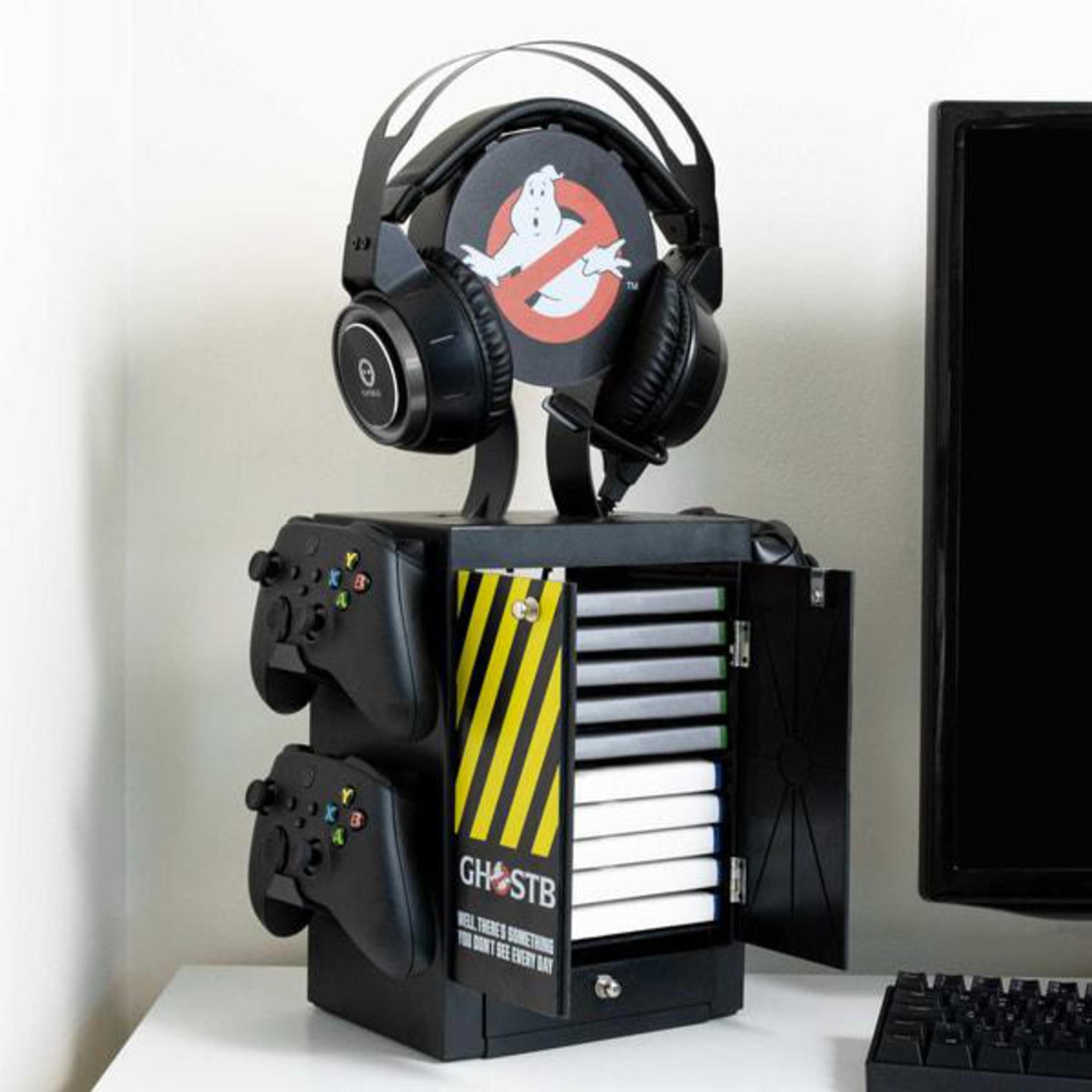 Ghostbusters-Gaming-Ständer, Kopfhörer oben, Controller seitlich, Spielhüllen innen, auf weißer Oberfläche.
