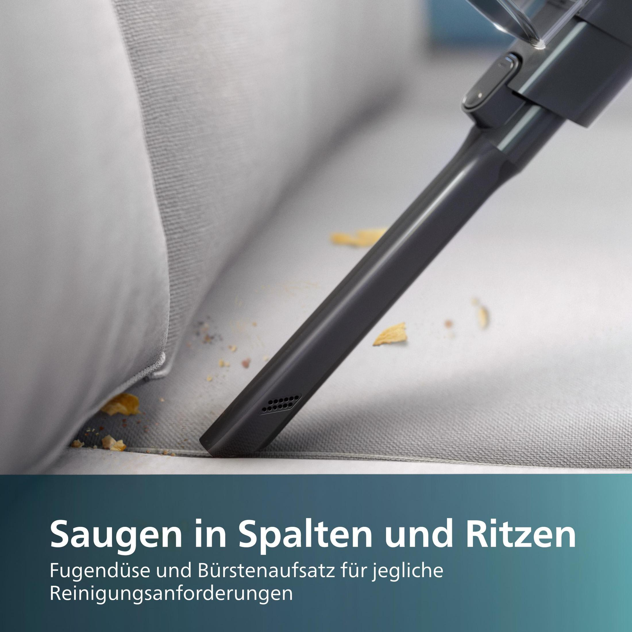 Een stofzuigmond reinigt een grijze bank met zichtbare kruimels.