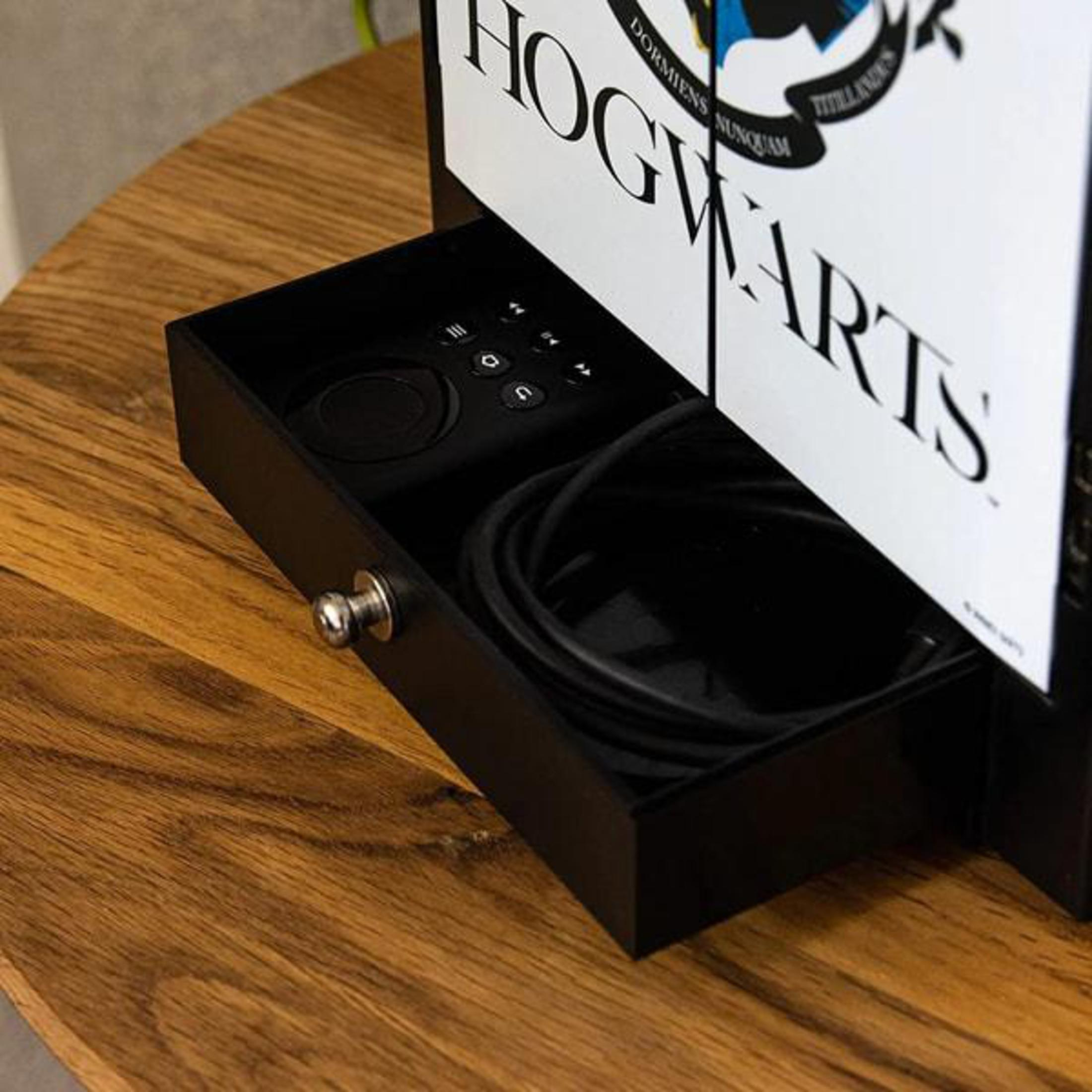 Schublade mit schwarzer Fernbedienung und Kabeln in einem Hogwarts-Zubehörschrank.