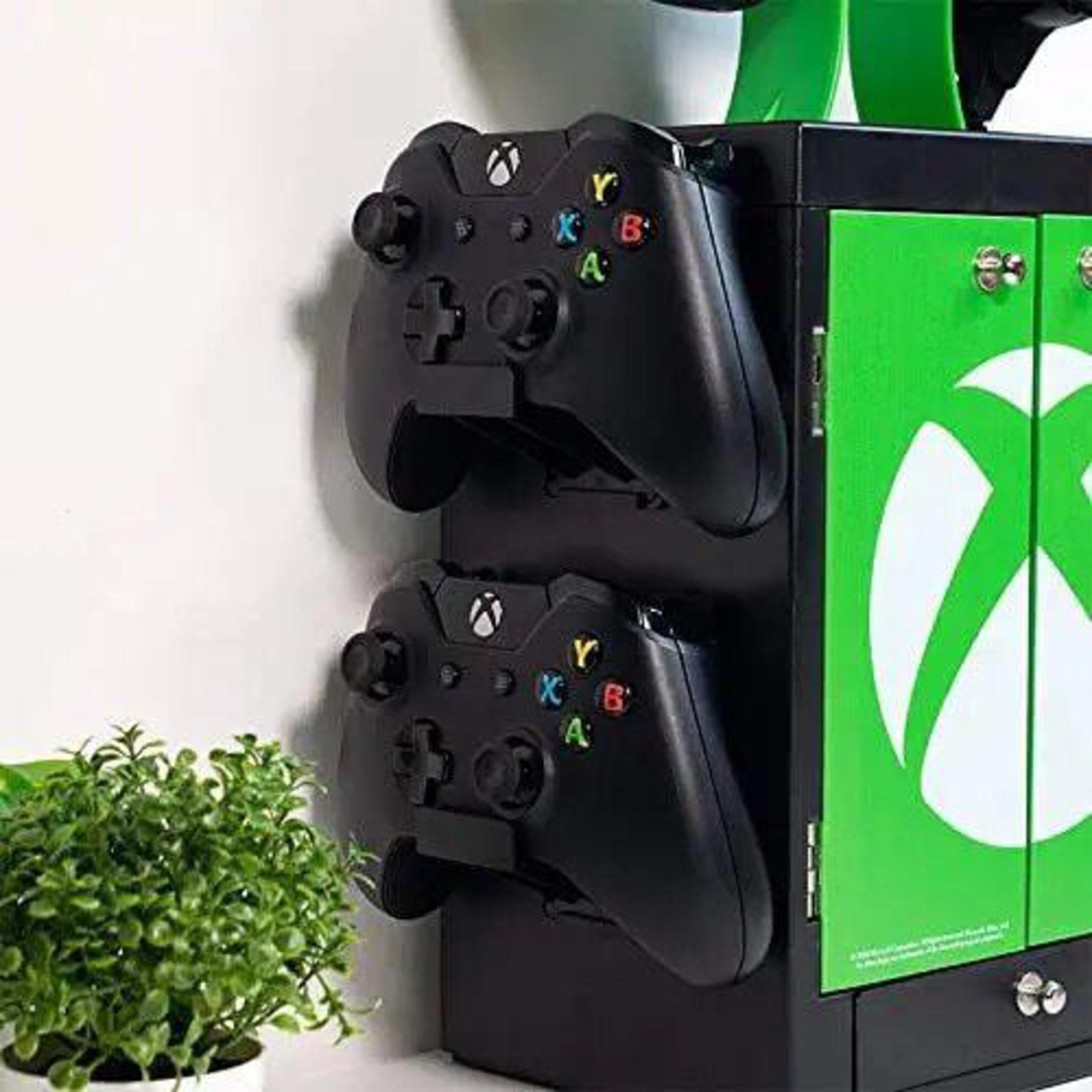 Nahaufnahme eines Xbox-Spieleständers mit zwei schwarzen Controllern. Grün und Schwarz.