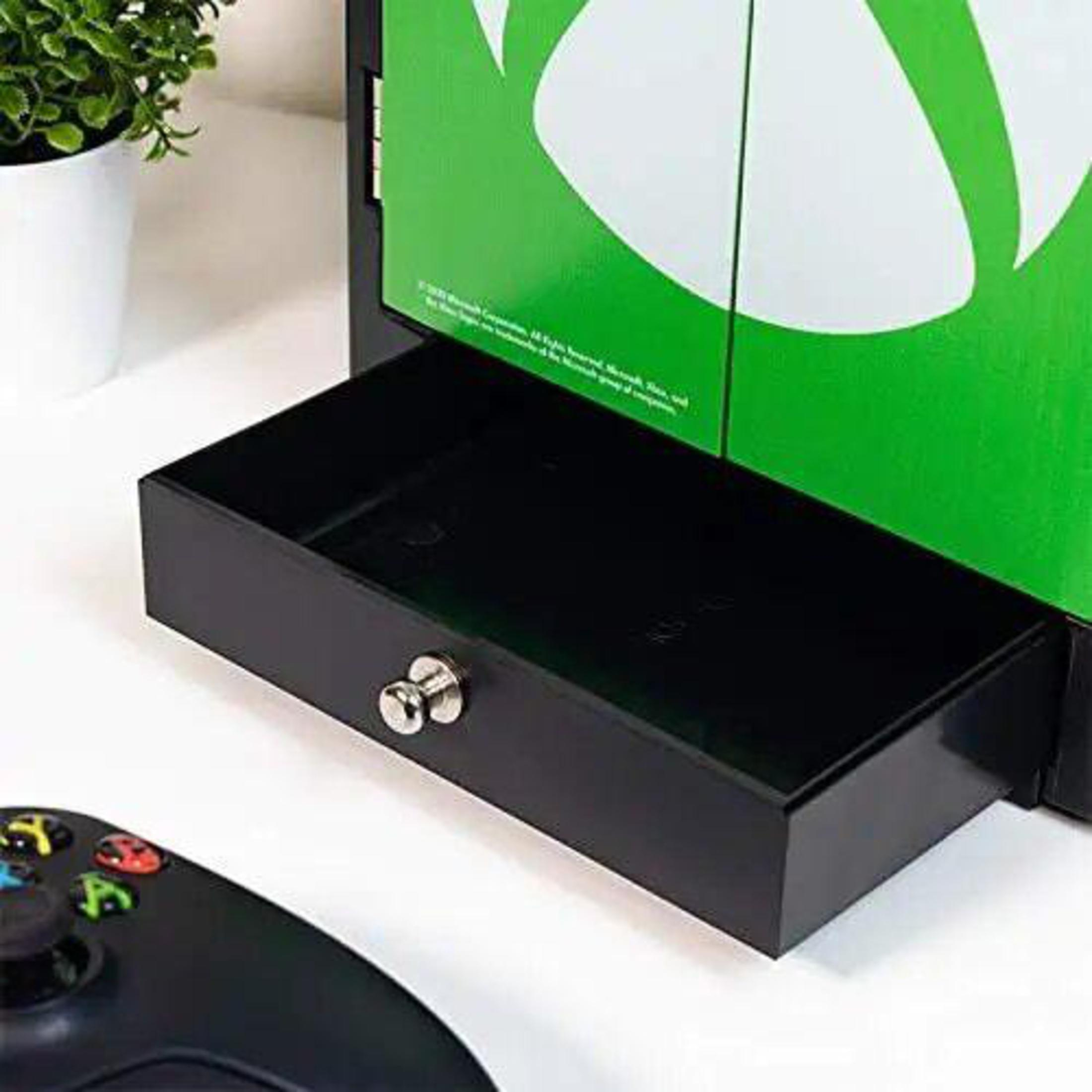 Schwarze Schublade des Xbox-Spielständers mit silbernem Schloss. Grünes Logo an der Schranktür.