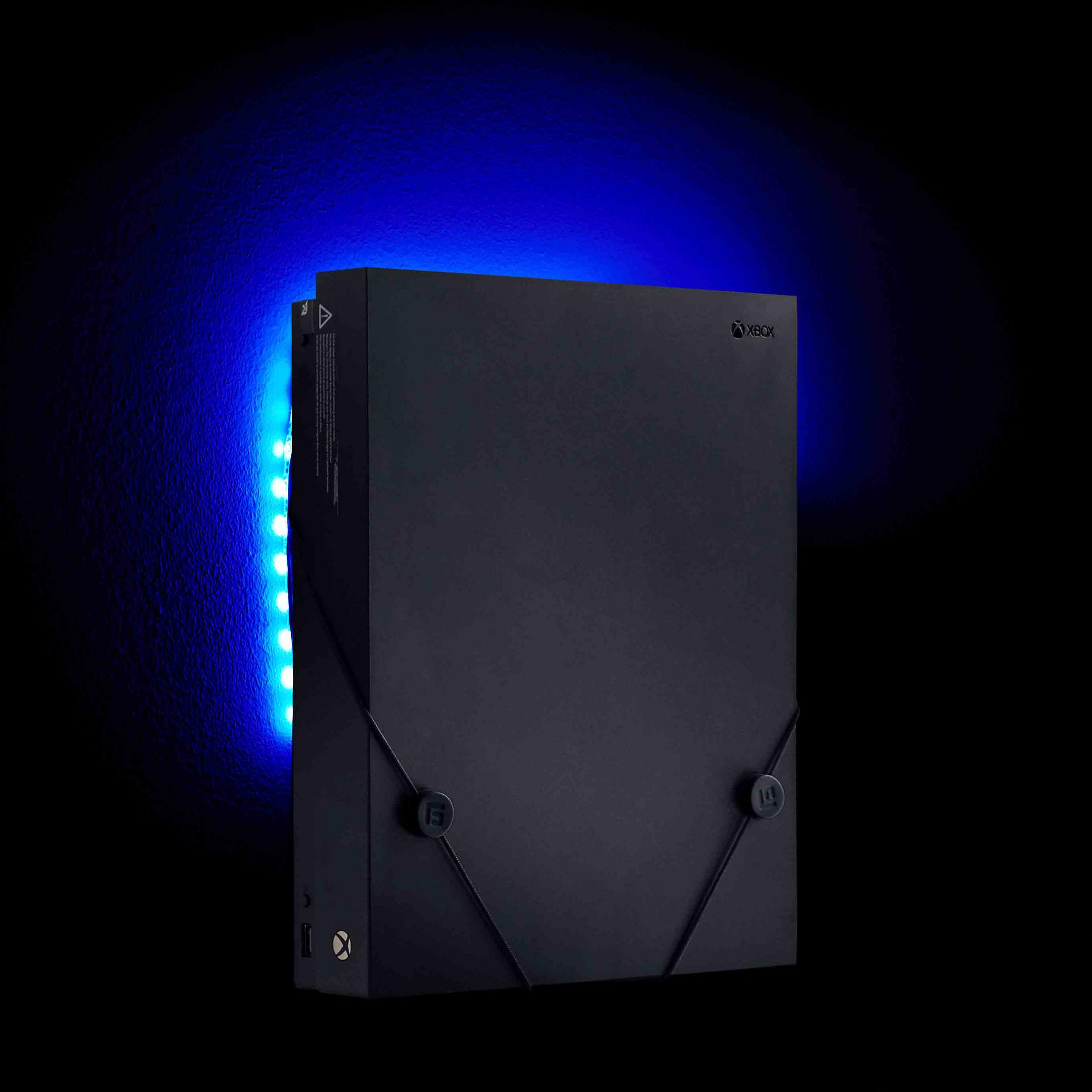 Schwarze Xbox-Konsole mit blauem Licht dahinter. Xbox-Logo sichtbar. Dunkler Hintergrund.