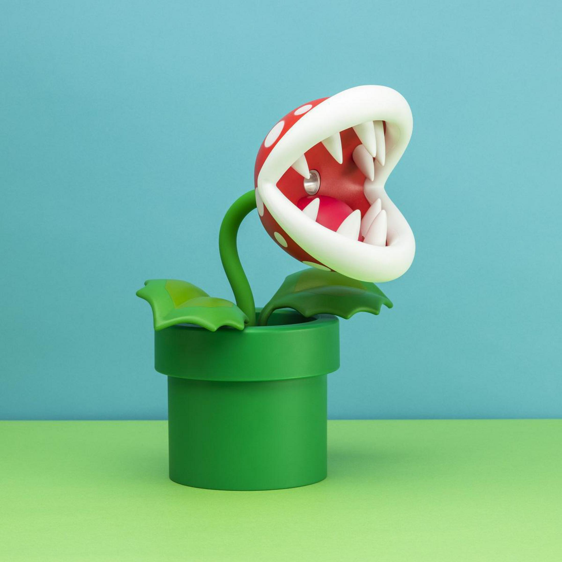 Zabawka Piranha Plant z czerwonymi ustami i białymi zębami, w zielonej doniczce, na niebieskim tle.