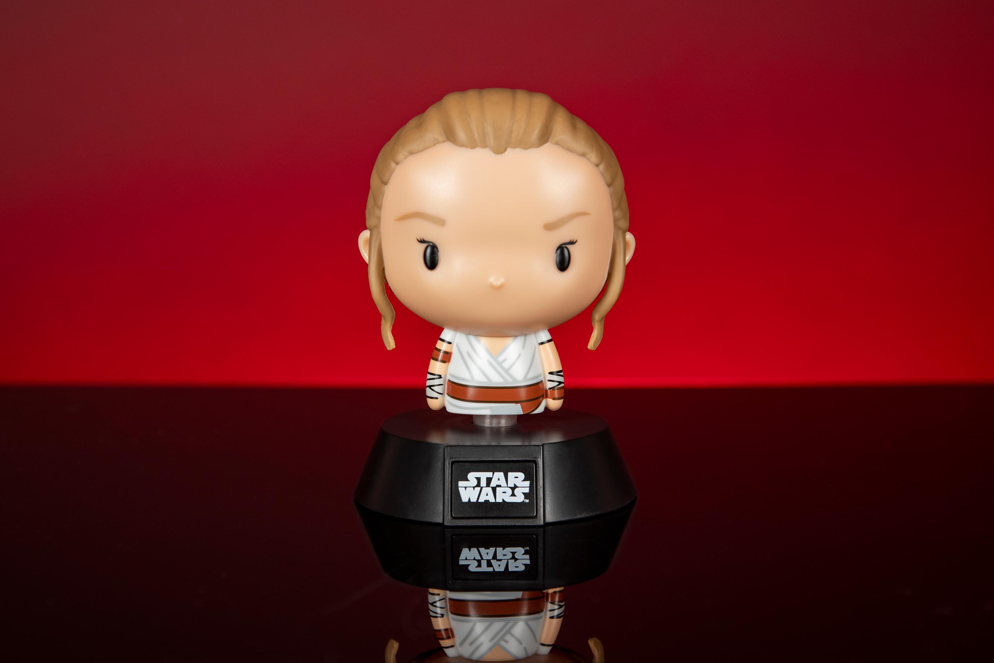 Figura de Rey bobblehead sobre una base negra. La figura es de piel clara con un atuendo blanco, fondo rojo.