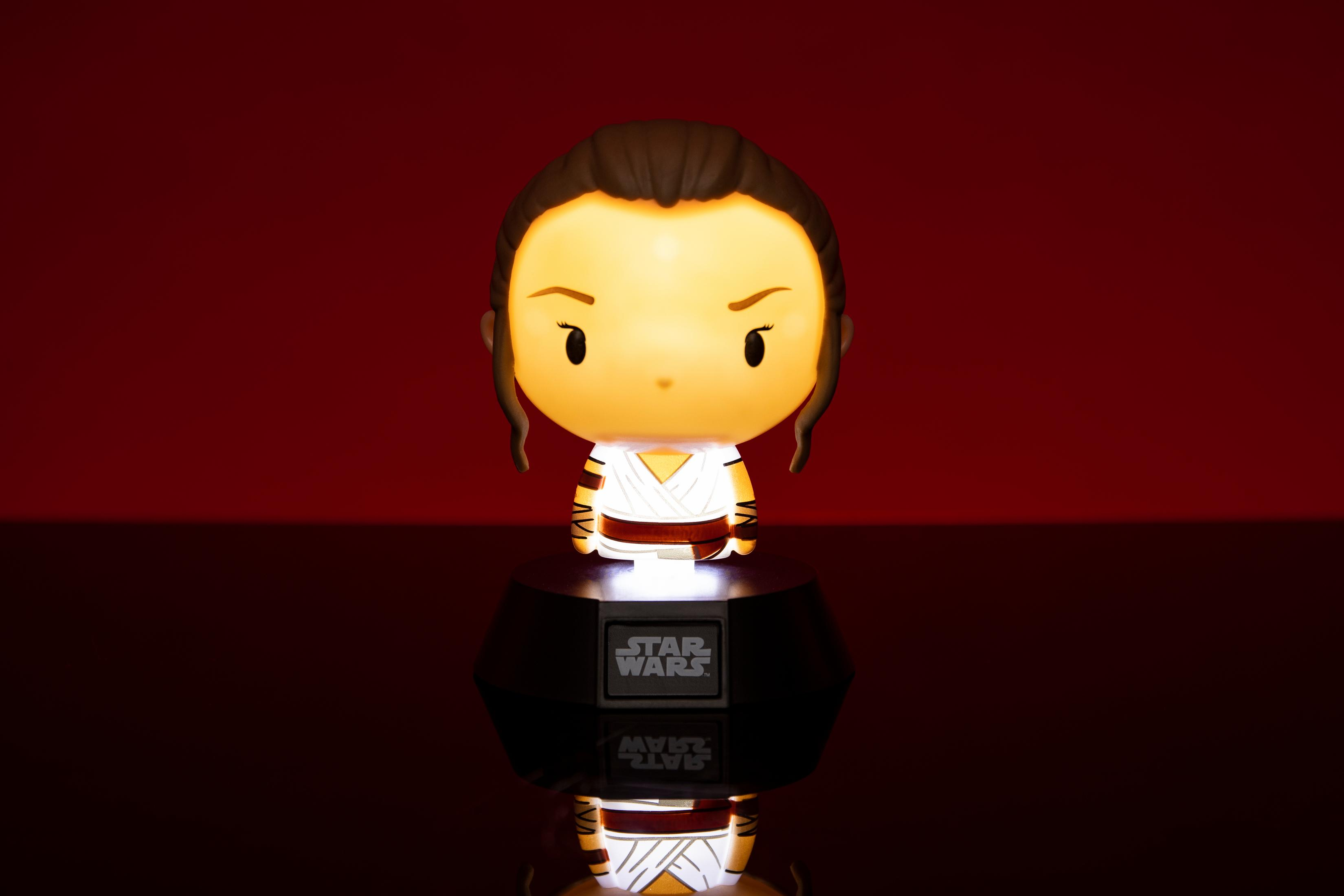 Figura de Rey iluminada con rostro brillante, sobre un soporte. Fondo rojo y superficie reflectante.