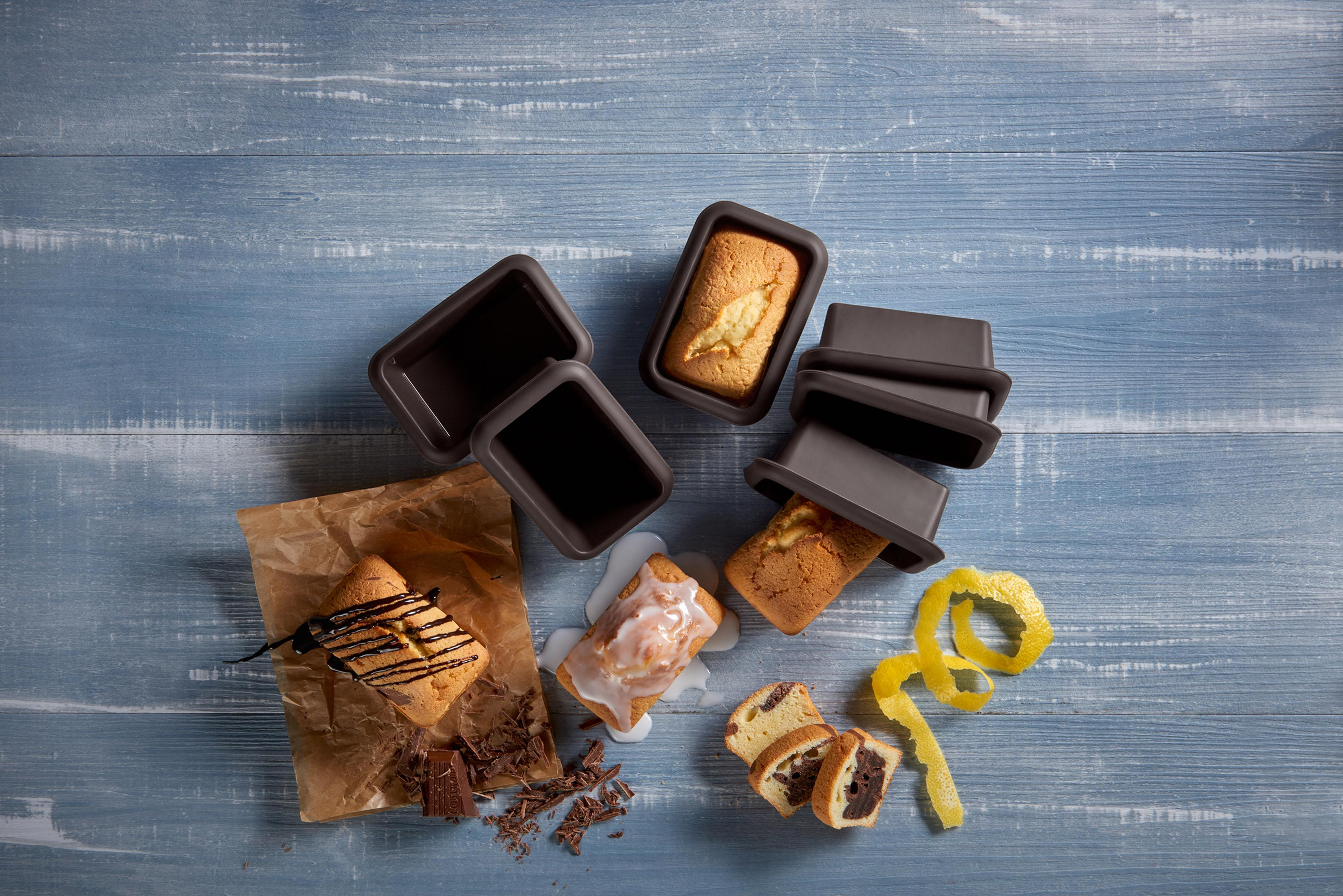 Mini babeczki, niektóre lukrowane, z czekoladą i skórką z cytryny, na drewnianej powierzchni.