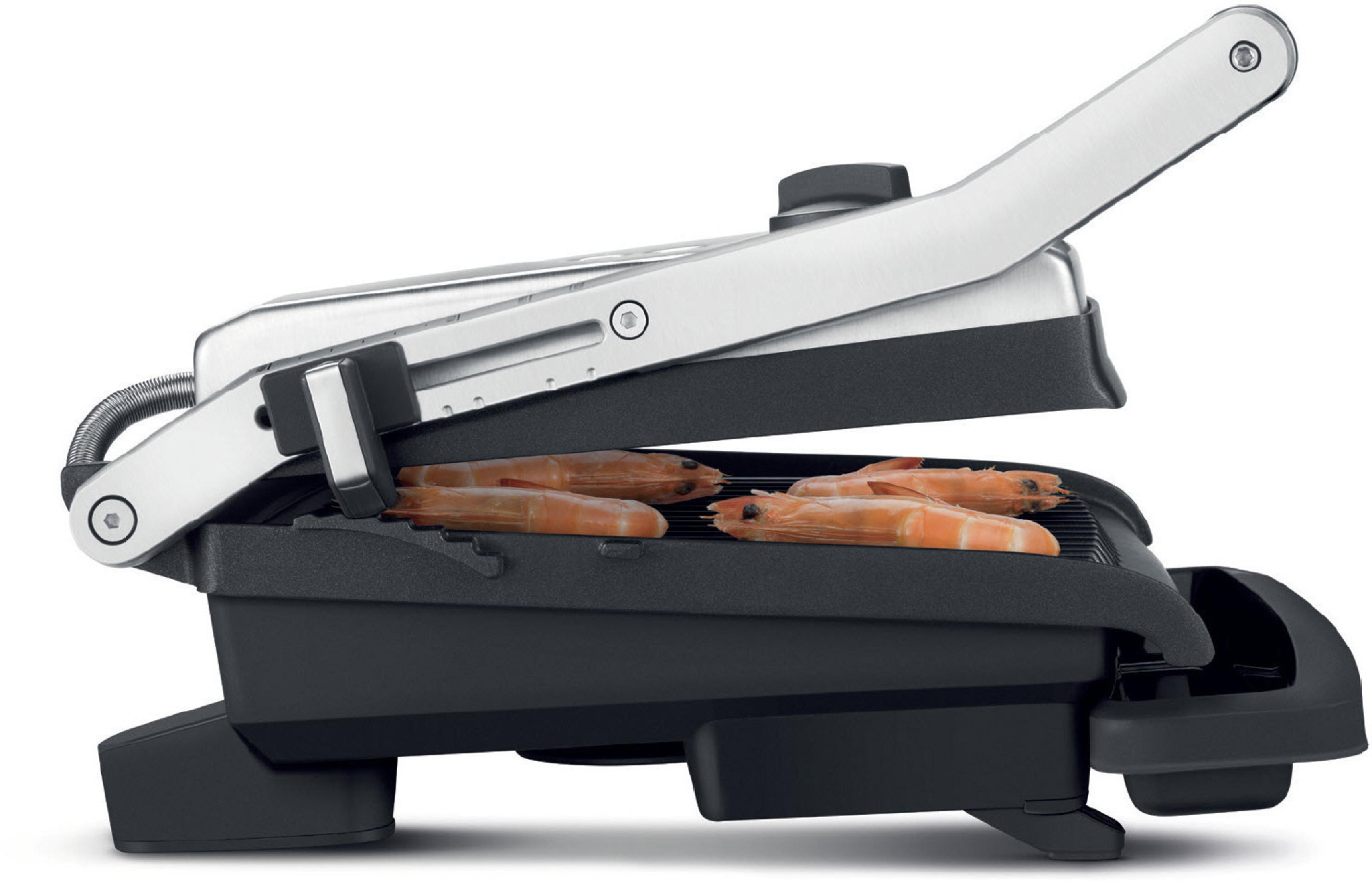Eine Panini-Presse mit geöffnetem Deckel, die gegrillte Garnelen zeigt. Die Presse ist silber und schwarz.