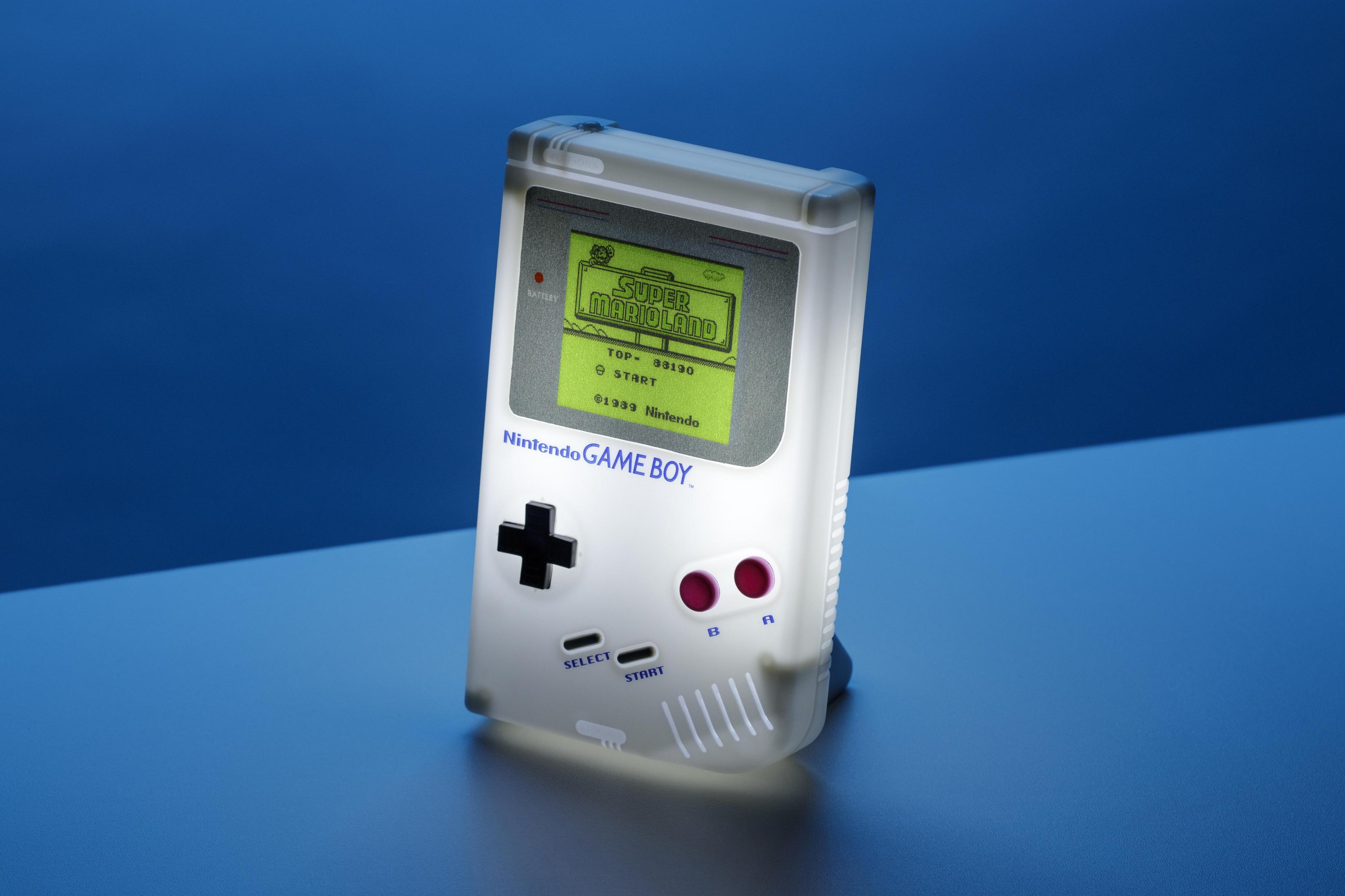Lámpara Game Boy blanca, pantalla de Super Mario Land, fondo azul.