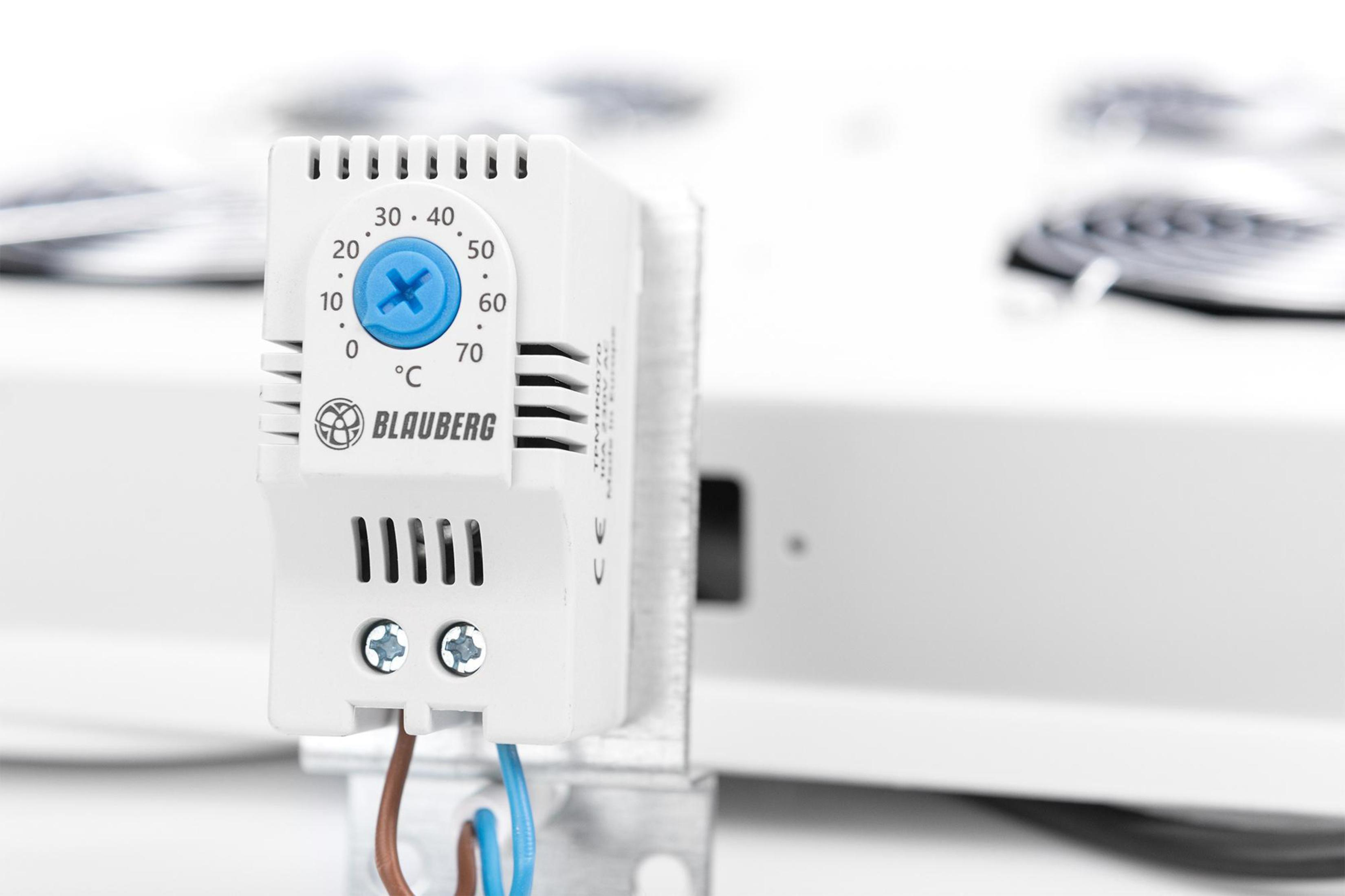 Ein weißer Thermostat mit blauem Zifferblatt zeigt die Temperatur in Celsius an. Drähte sind unten verbunden.