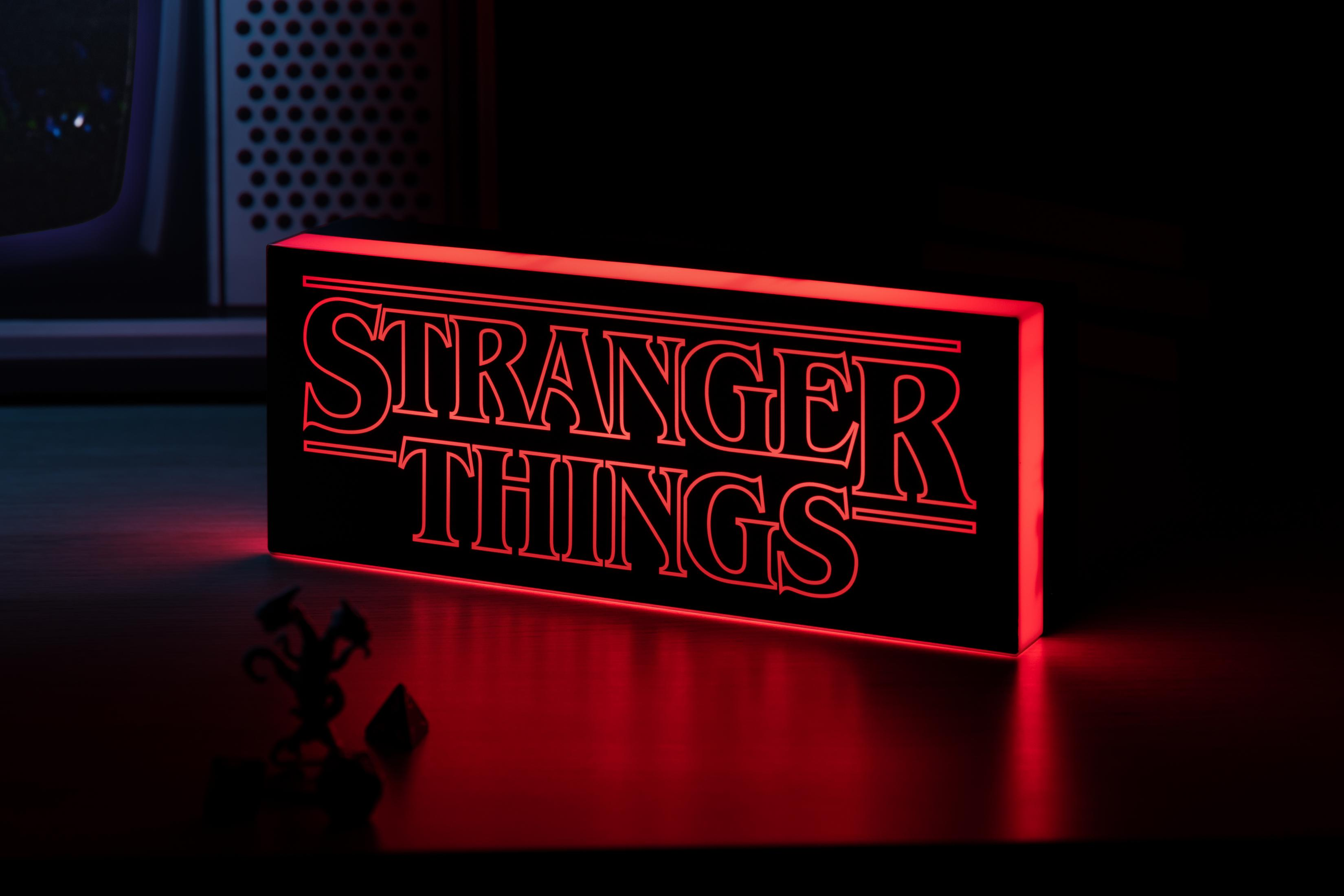 Beleuchtetes Stranger Things-Schild auf dunkler Oberfläche. Roter Schein beleuchtet alles.