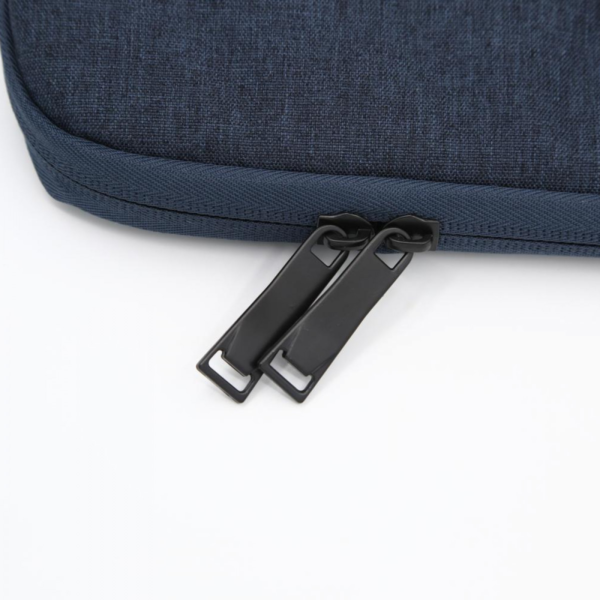 Zbliżenie granatowej torby z dwoma czarnymi suwakami zamków.