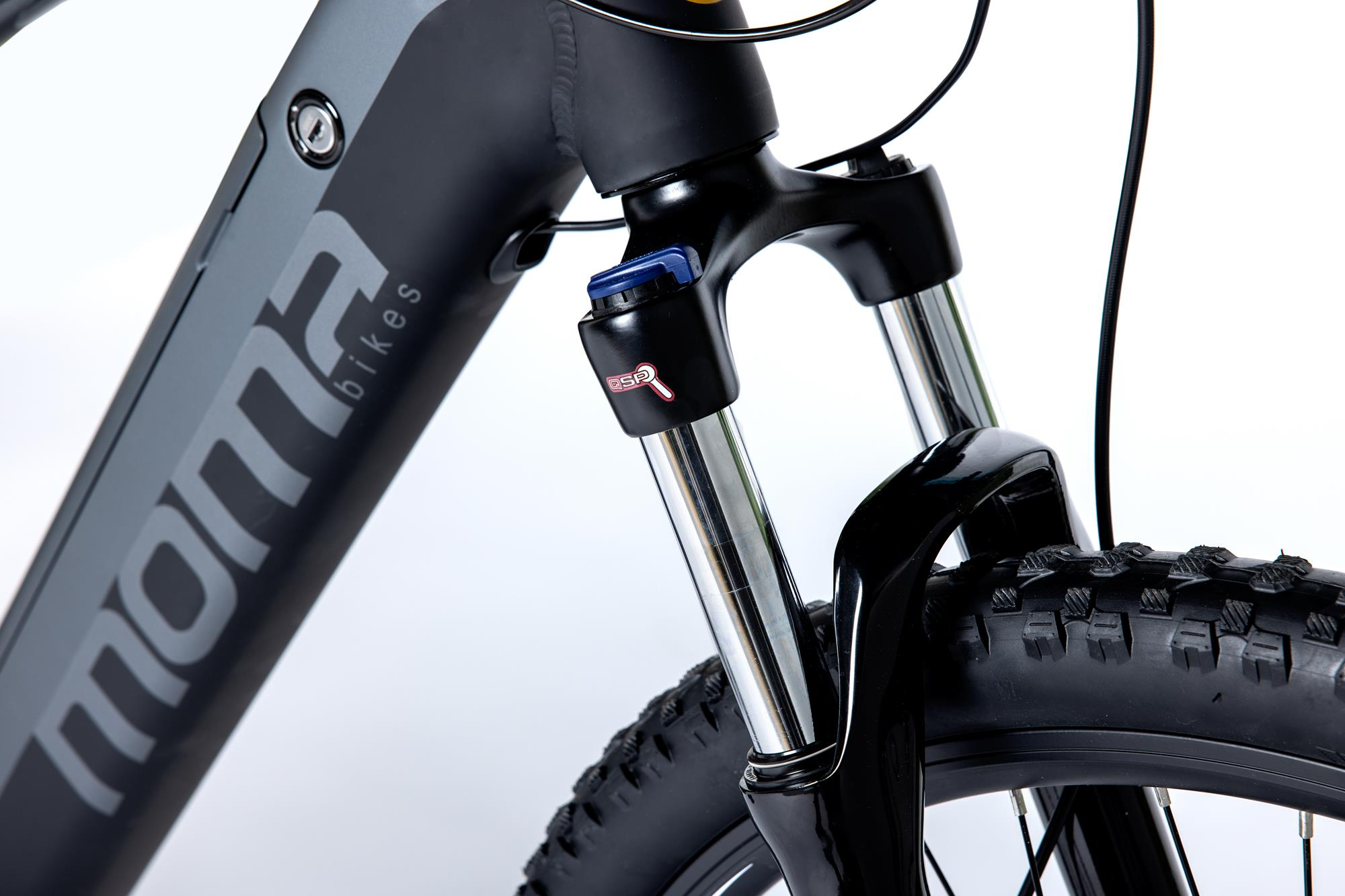 Schwarzer und grauer Mountainbike-Rahmen, Detail der Vorderradgabel. Weißer Hintergrund. Mona Bikes Logo sichtbar.