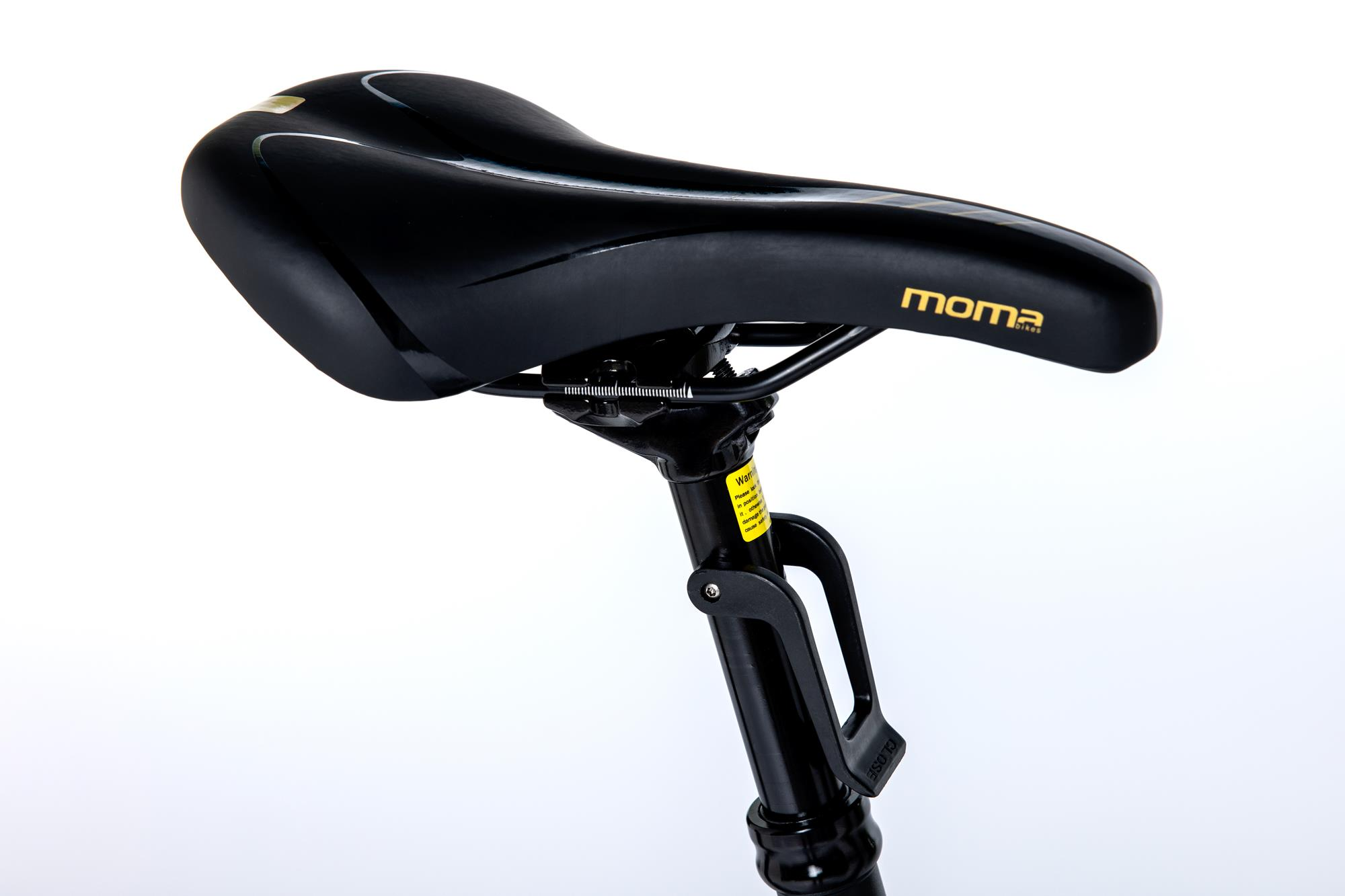 Sella nera per bici, forma curva. Logo 'moma' dorato. Reggisella nero, parti metalliche visibili.