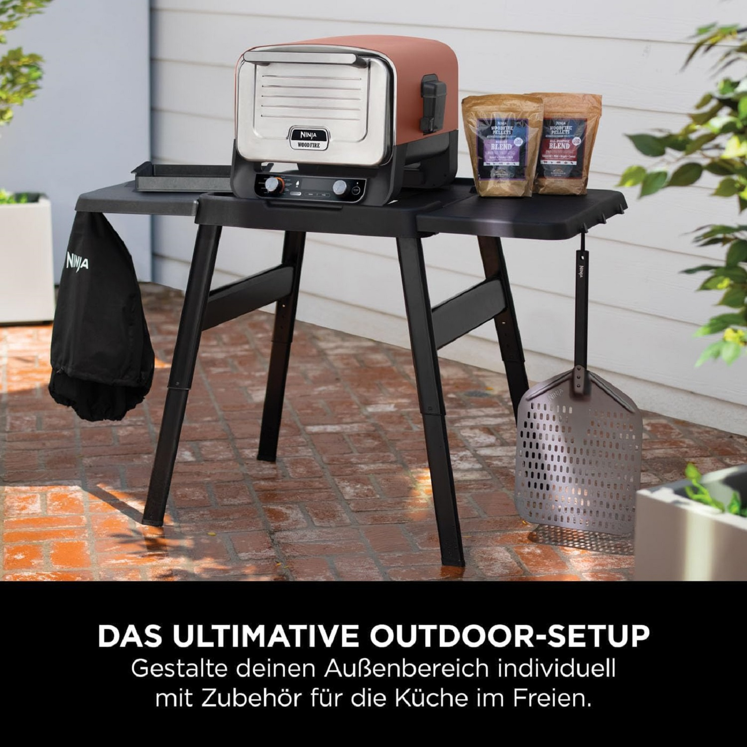 Zestaw do gotowania na świeżym powietrzu z grillem i akcesoriami na czarnym stole. Tekst w języku niemieckim.