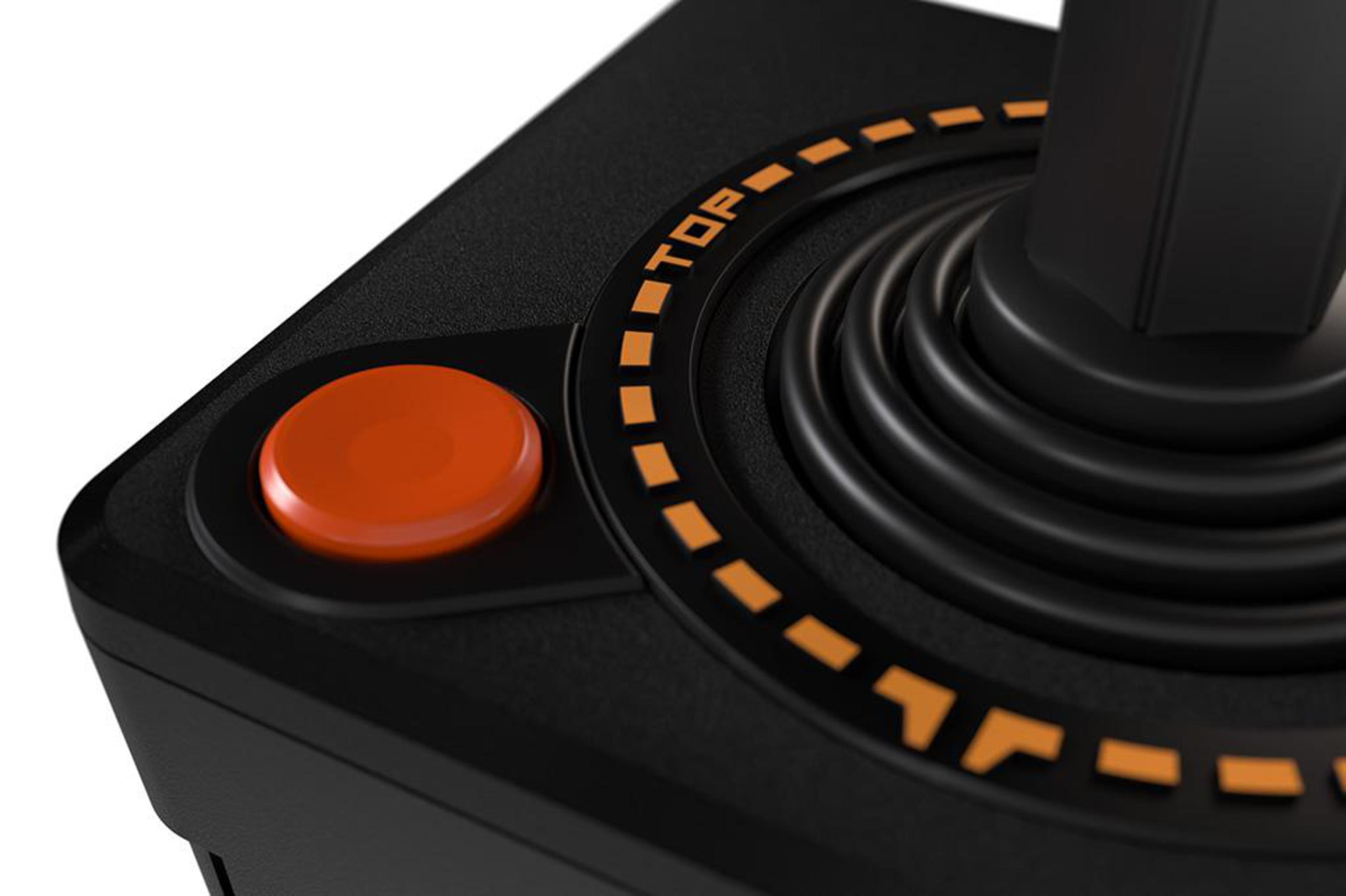 Zbliżenie czarnej podstawy joysticka Atari, pomarańczowy przycisk i pomarańczowy pierścień z etykietą. Widoczne słowo TOP.