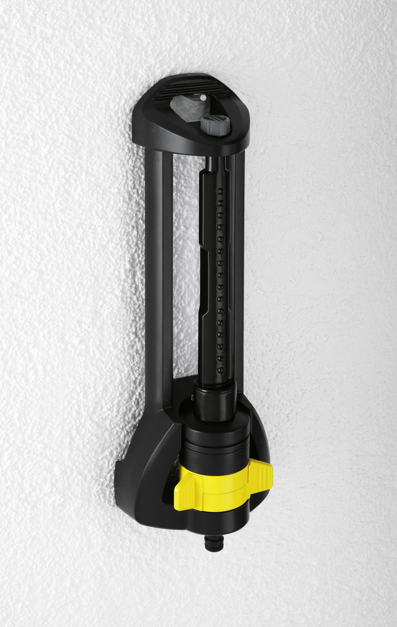 Ein schwarz-gelber Sprinkler an einer strukturierten weißen Wand. Er ist vertikal und hat ein gelbes Zifferblatt.