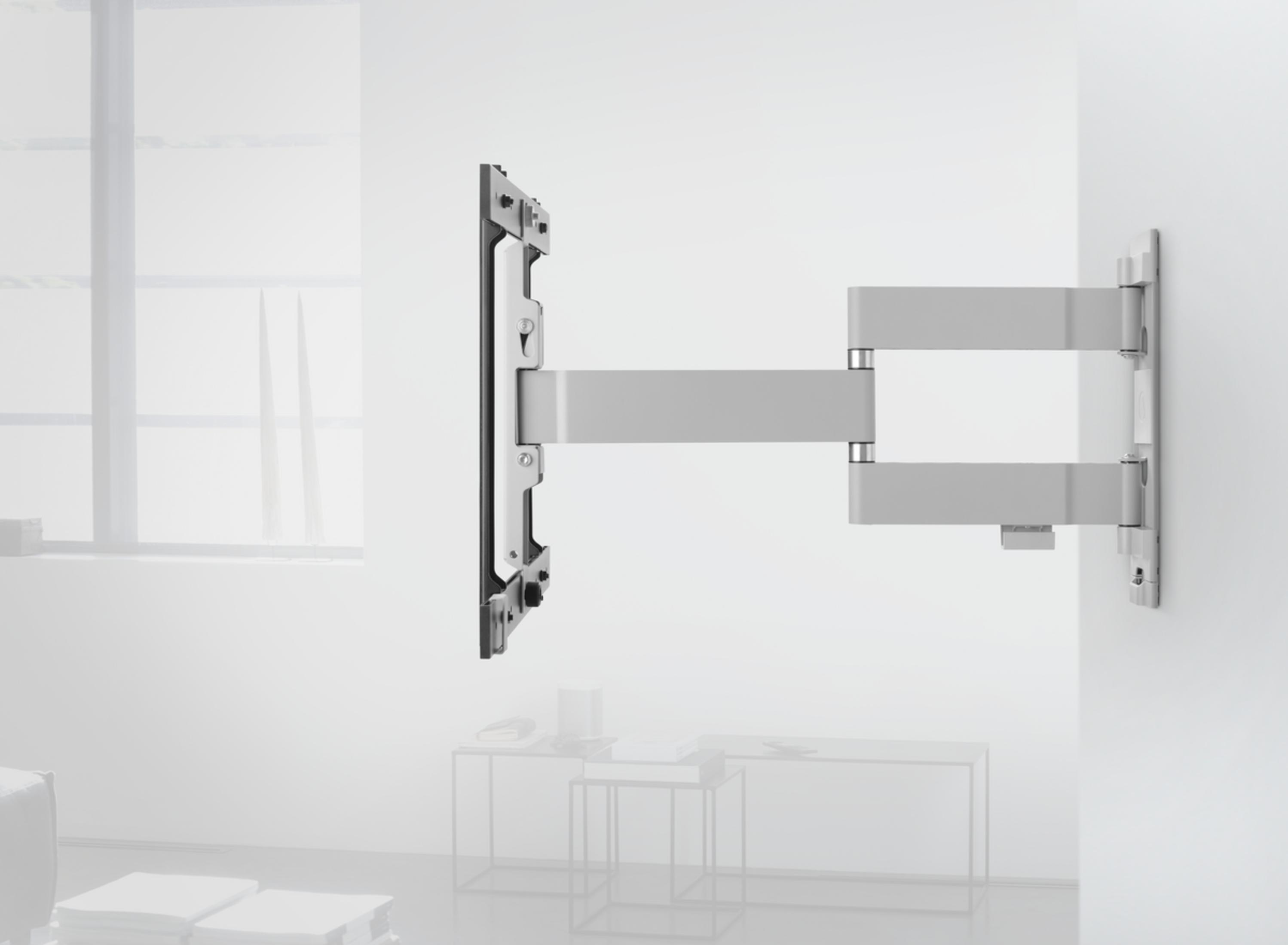 TV-Halterung, weiß, an einer Wand montiert, mit Fenster und Sofa im Hintergrund.