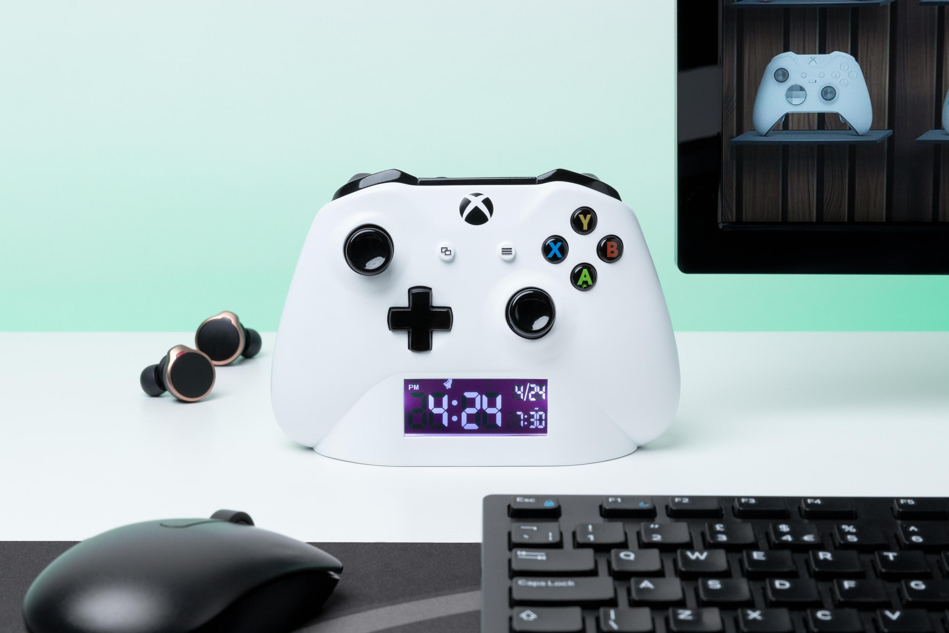 Weiße Xbox Controller-Uhr, Ohrhörer, Maus und Tastatur auf einem Schreibtisch.