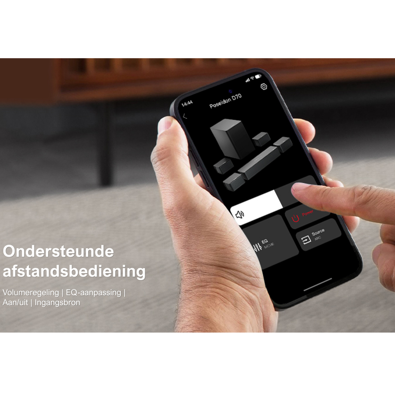 A hand holds a phone displaying an app interface. The app controls a sound system.