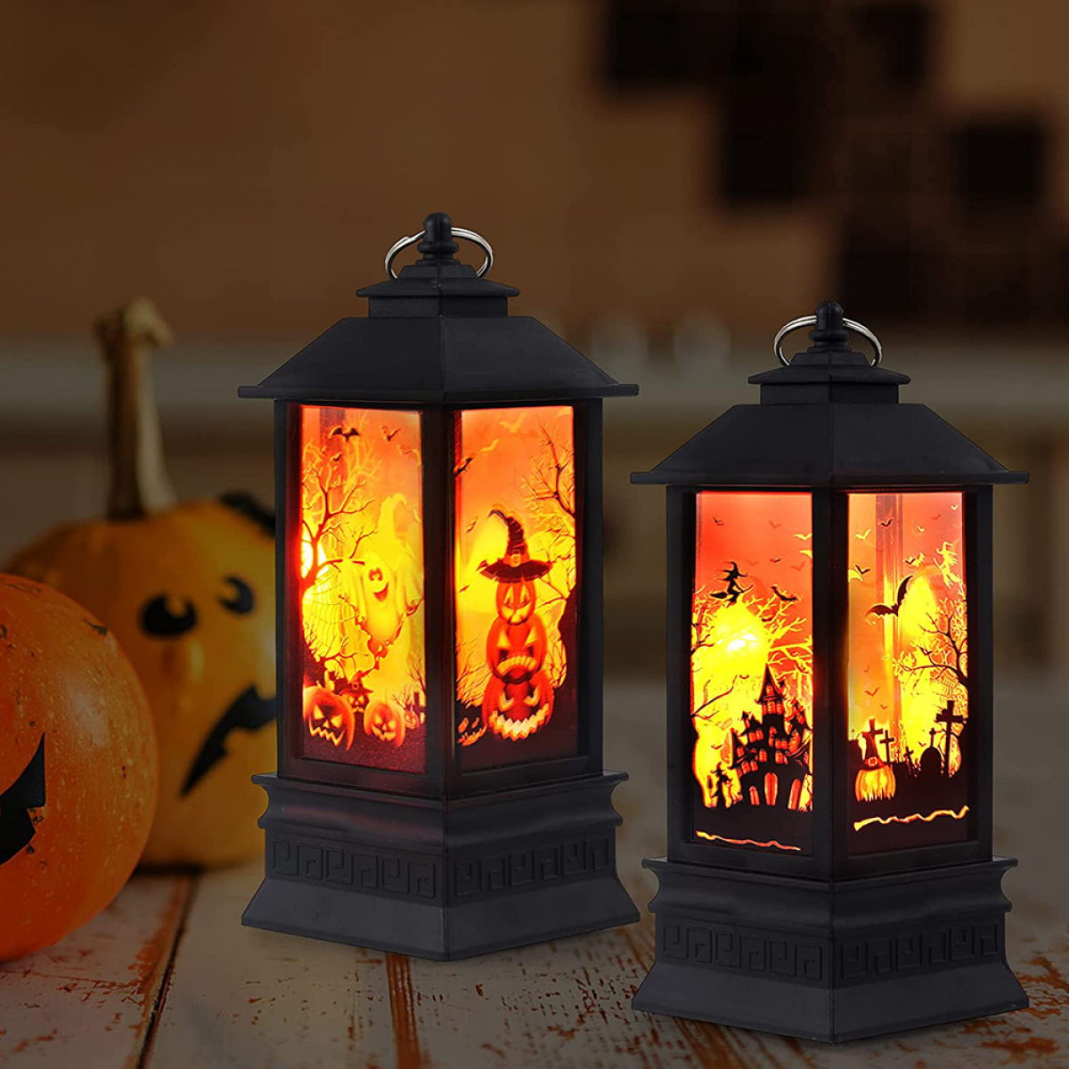 Zwei schwarze Halloween-Laternen mit orangefarbenen Szenen neben einem Kürbis.
