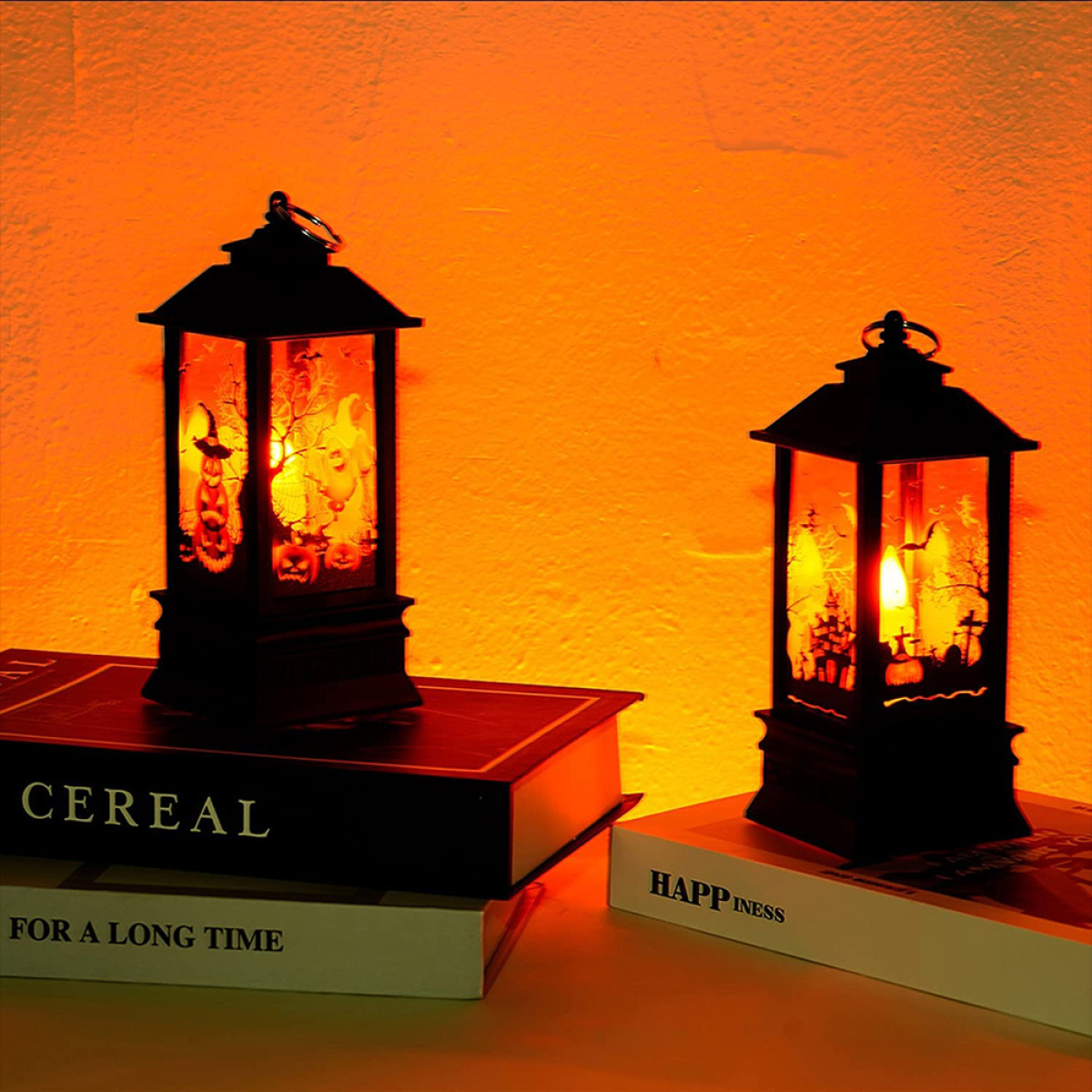Halloween-Laternen auf Büchern mit orangefarbenem Hintergrund.