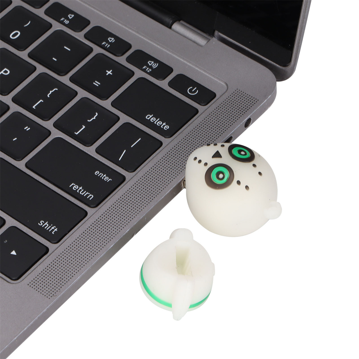 Weißer USB-Stick in Eulenform neben einer Laptop-Tastatur, mit abgetrenntem Kopf.