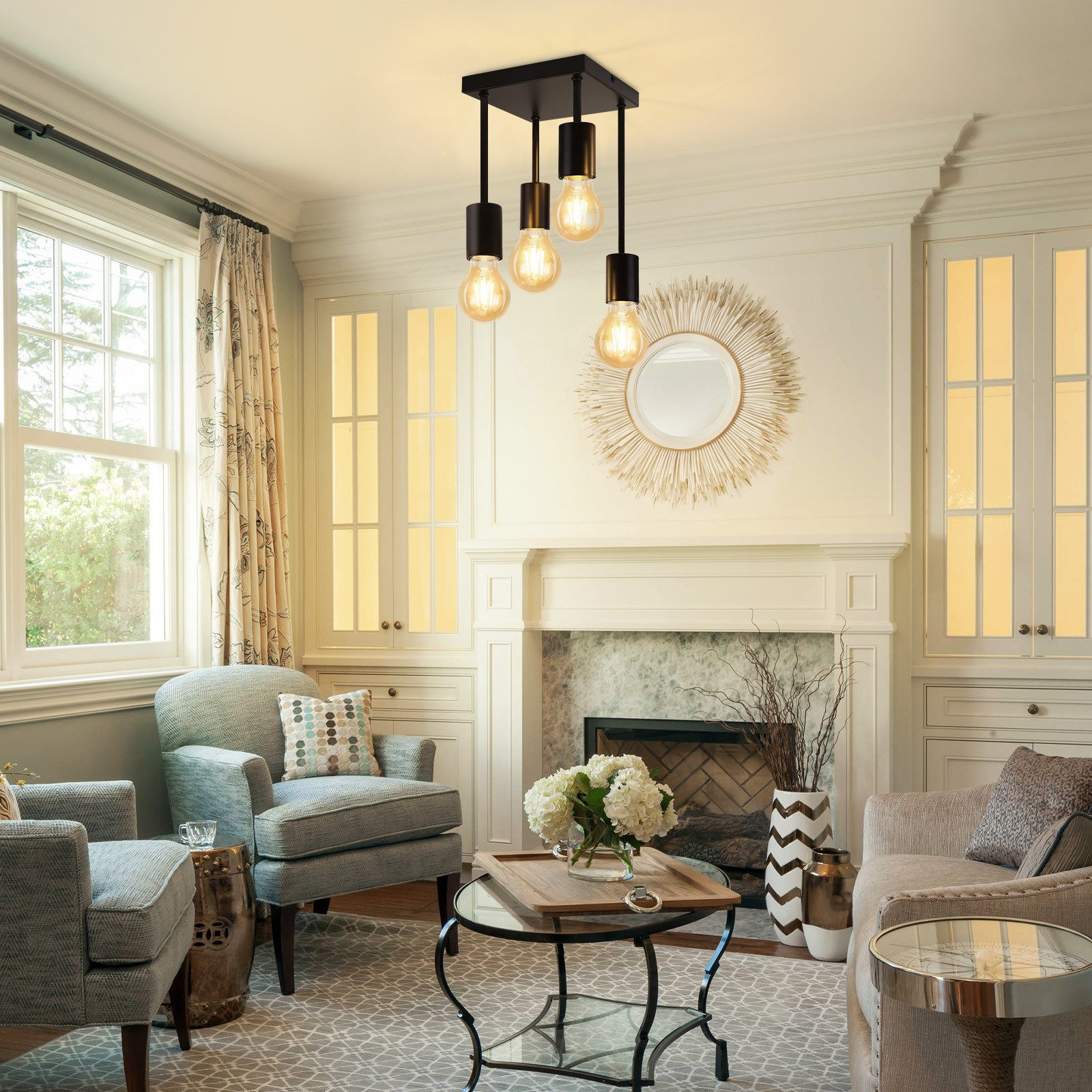 Salon z żyrandolem, fotelami, stołem, kominkiem i oknami. Jasne ściany i wystrój.