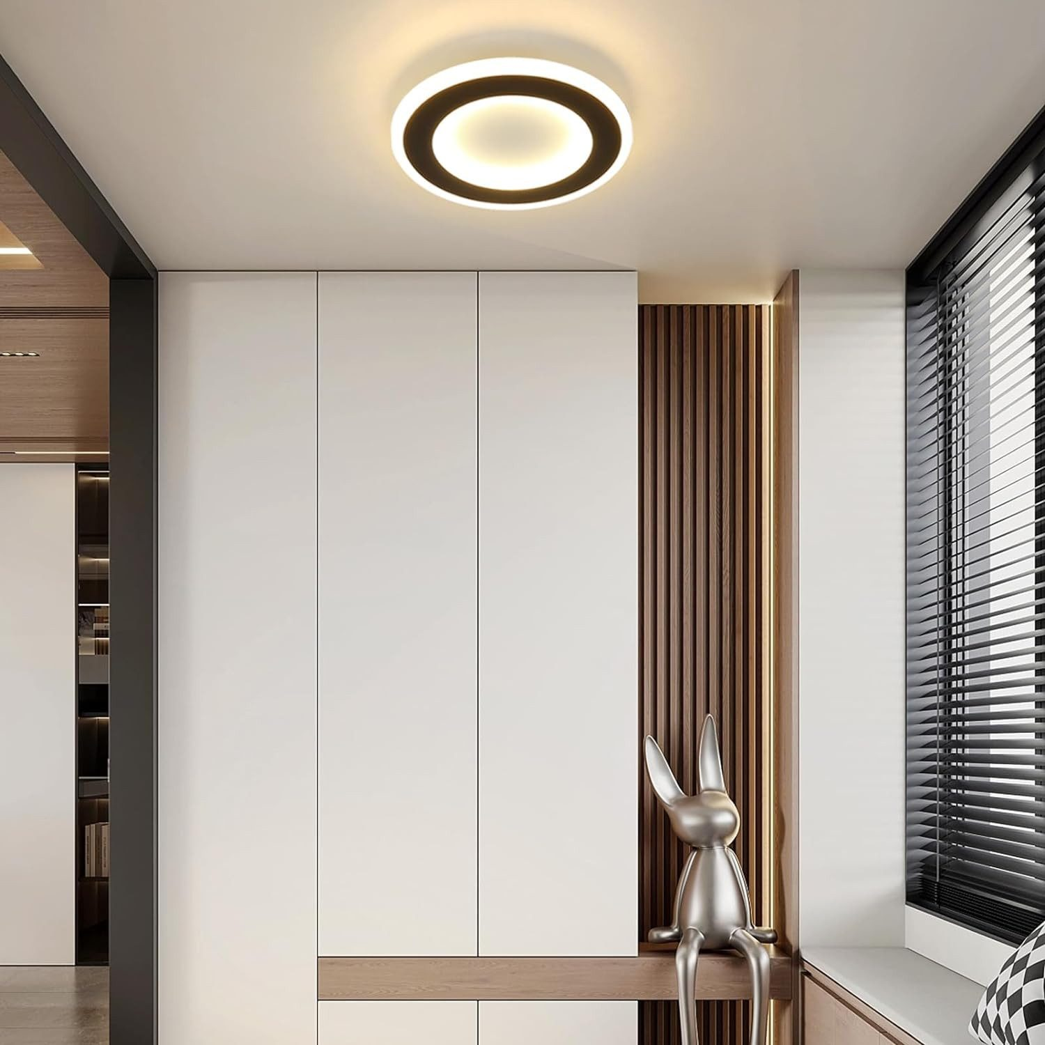 Biała lampa sufitowa z czarnym pierścieniem i srebrną figurą poniżej.