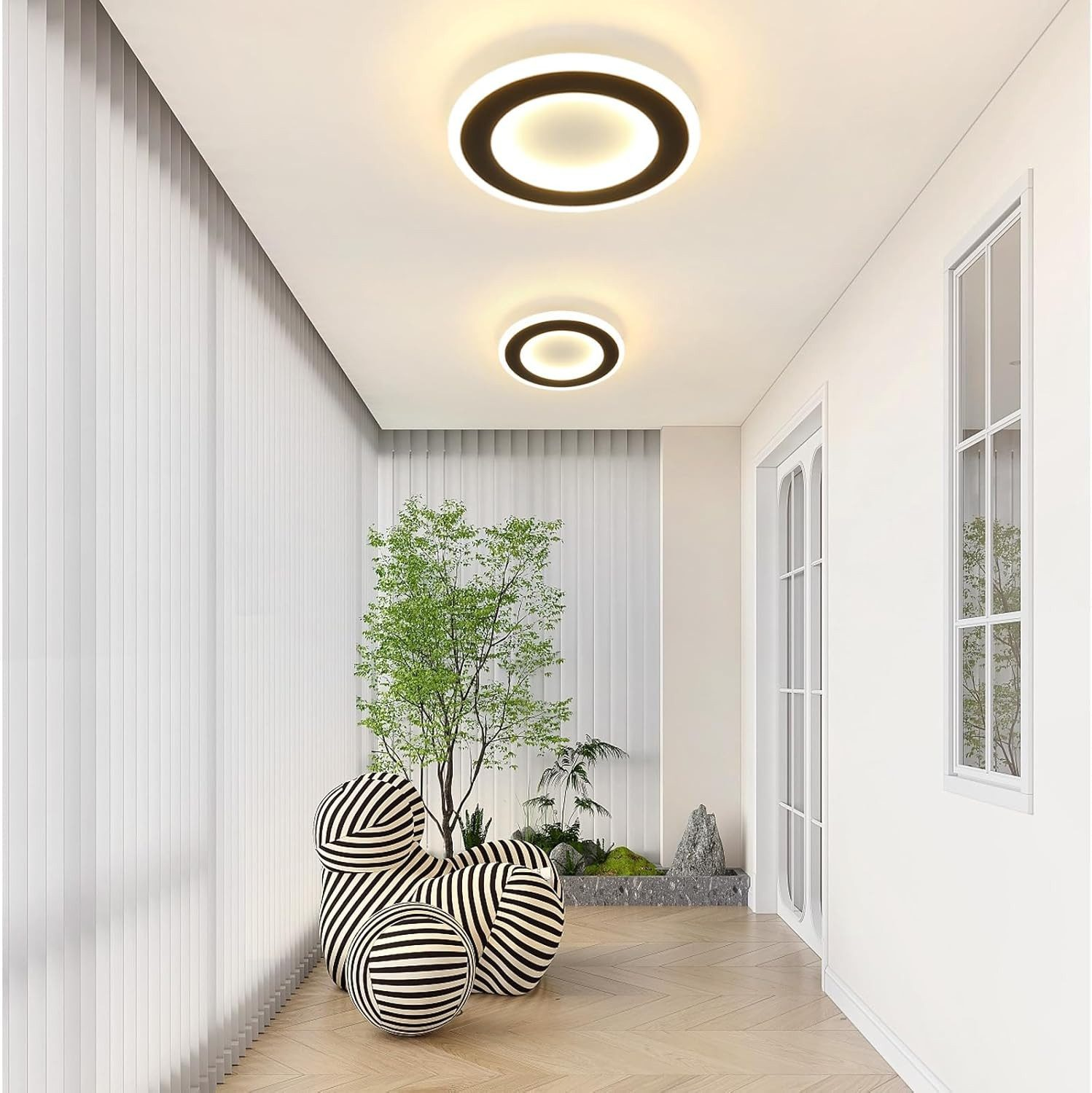 Korytarz z trzema lampami sufitowymi. Jest roślina i paski kul. Białe ściany i podłoga.