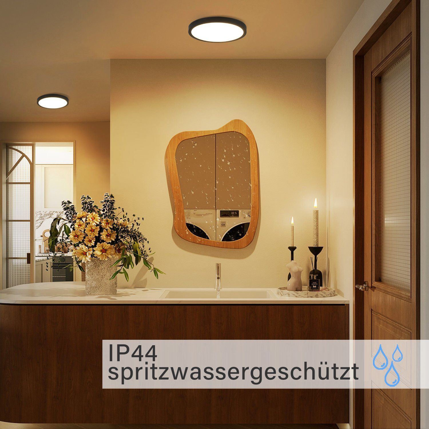 Interni con due plafoniere. Specchio, candele, fiori e un mobile in legno. Parete bianca.