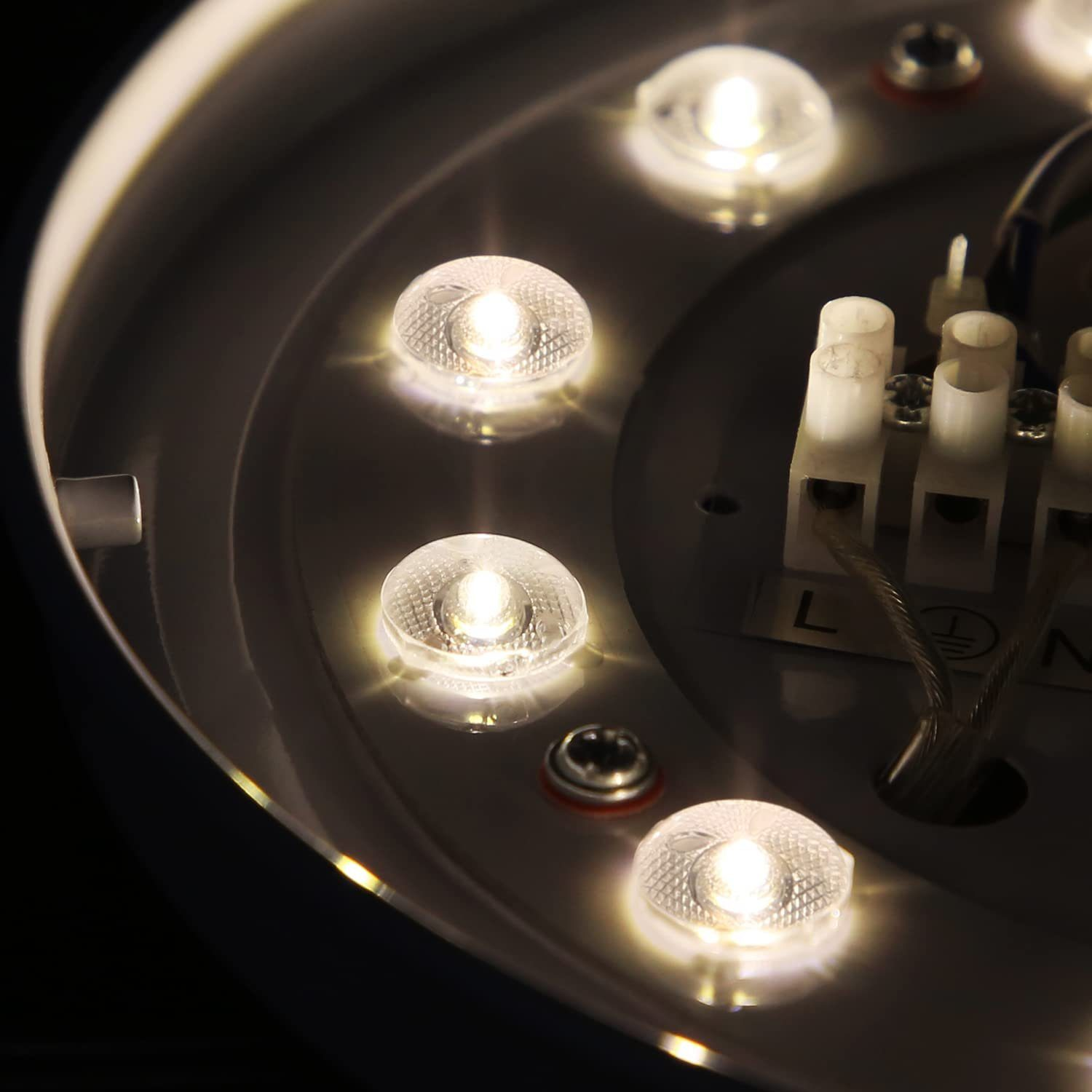 Zbliżenie białej lampy sufitowej z kilkoma małymi światłami i widocznymi elementami elektrycznymi.