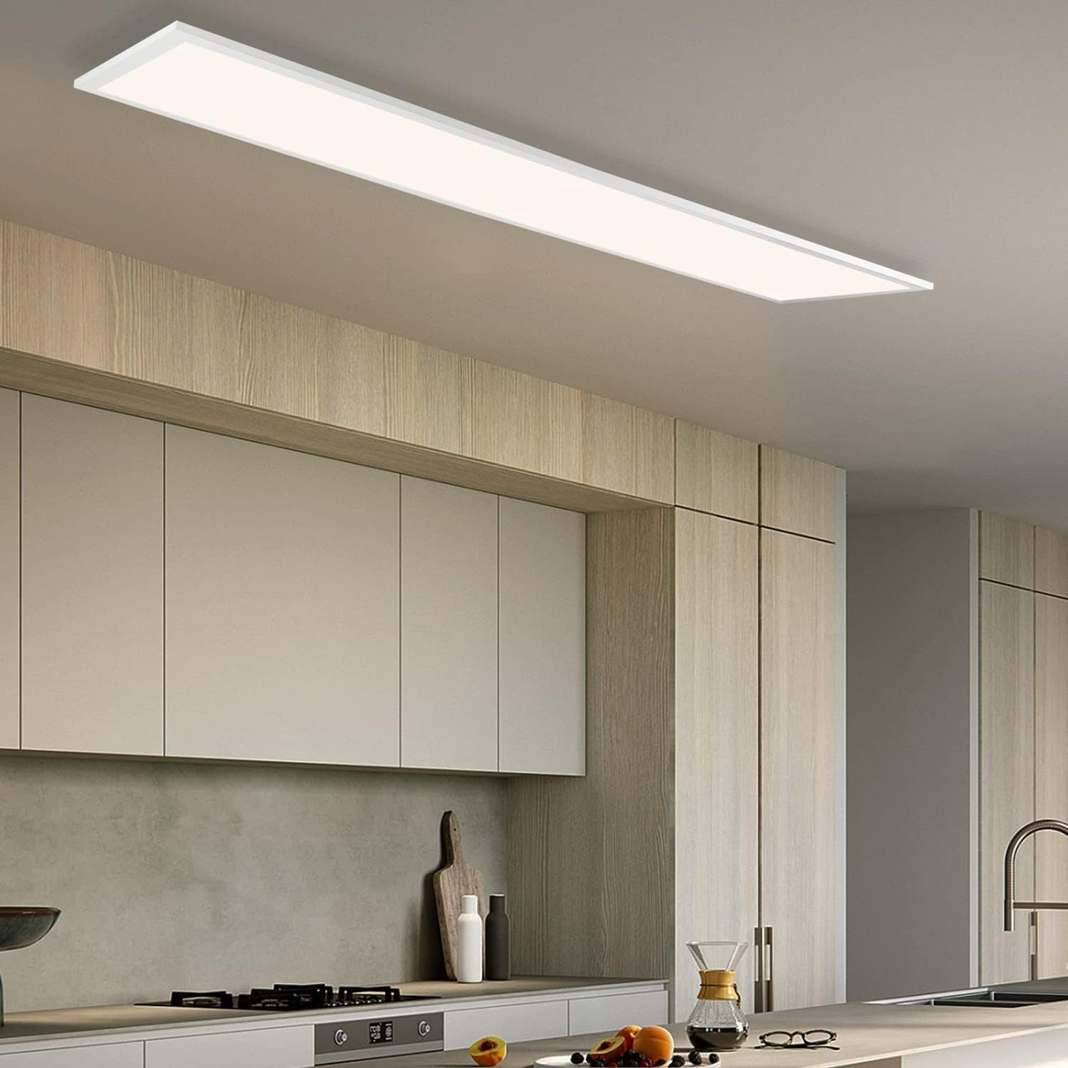 Cucina con una lunga plafoniera rettangolare. I mobili sono in legno chiaro, un piano di lavoro grigio chiaro e un lavandino.
