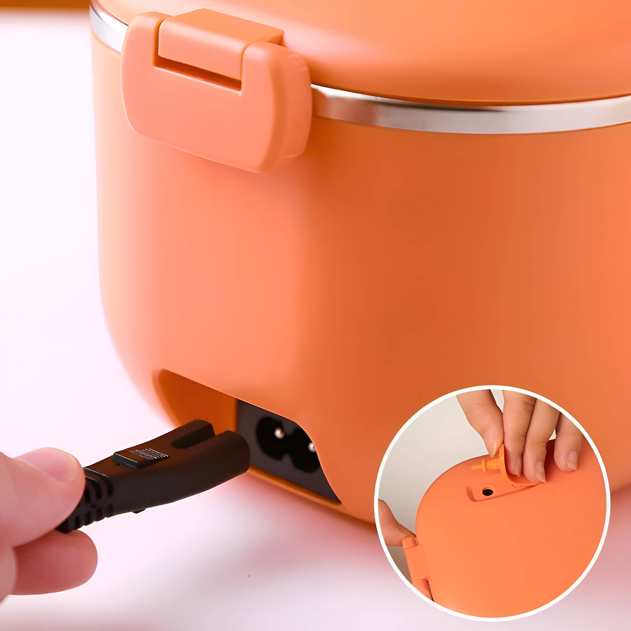 Orangene Lunchbox, in die ein schwarzer Stecker gesteckt wird. Eine Hand sichert die Oberseite.