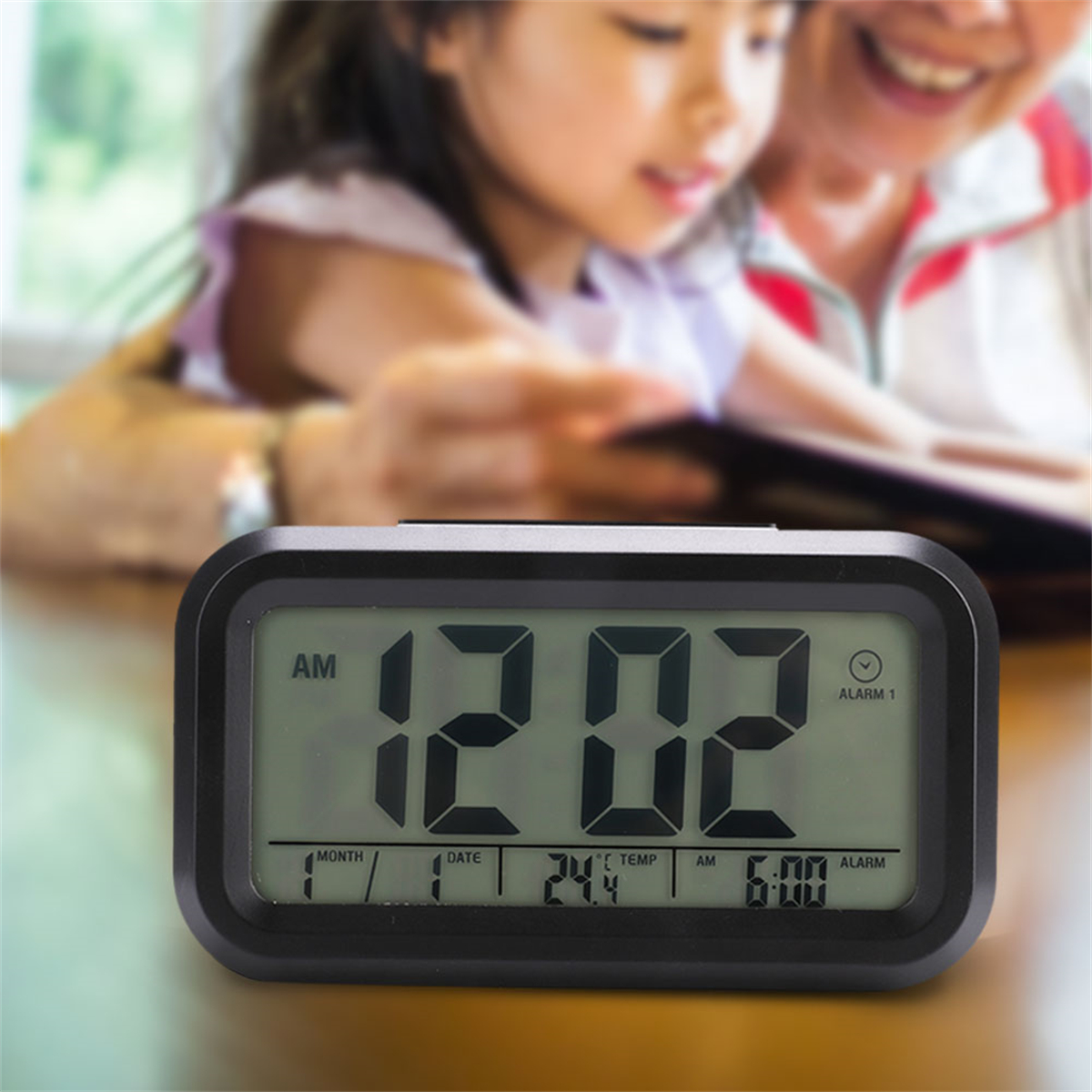 Digitaluhr mit 12:02 Uhr AM. Im Hintergrund ein verschwommenes Kind und ein Erwachsener, die ein Buch lesen.