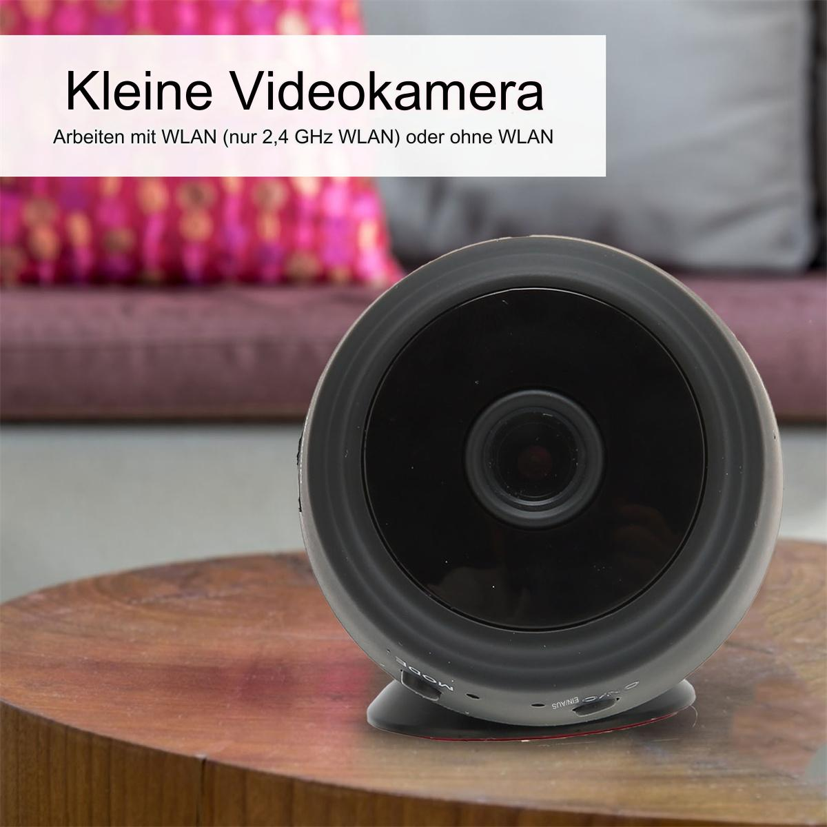 Eine kleine schwarze Überwachungskamera mit Linse und kleinem Sockel, auf einem Tisch.