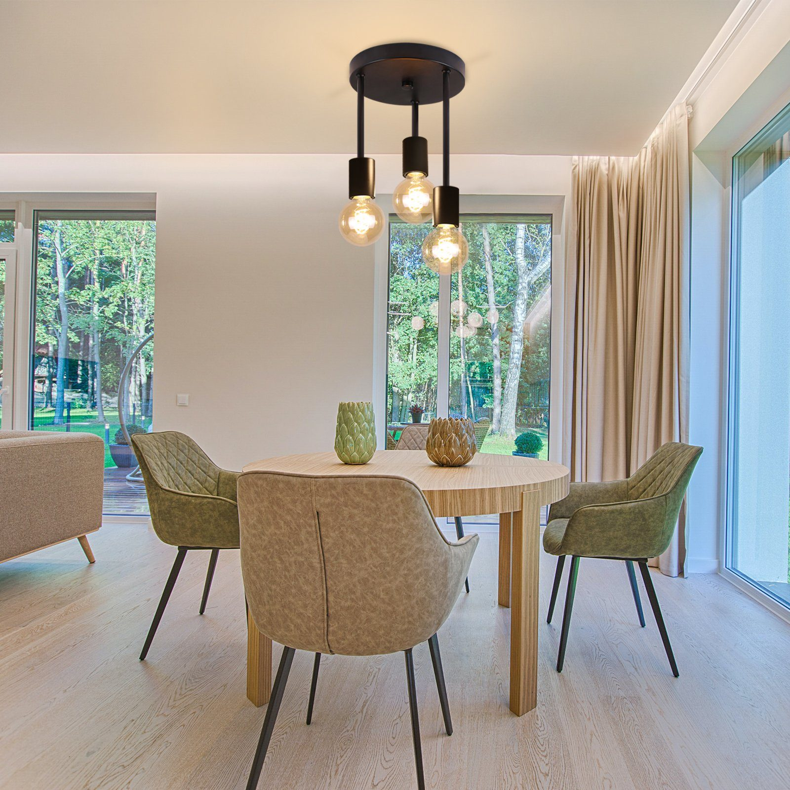 Jadalnia z okrągłym drewnianym stołem, krzesłami i lampą wiszącą z trzema odsłoniętymi żarówkami.