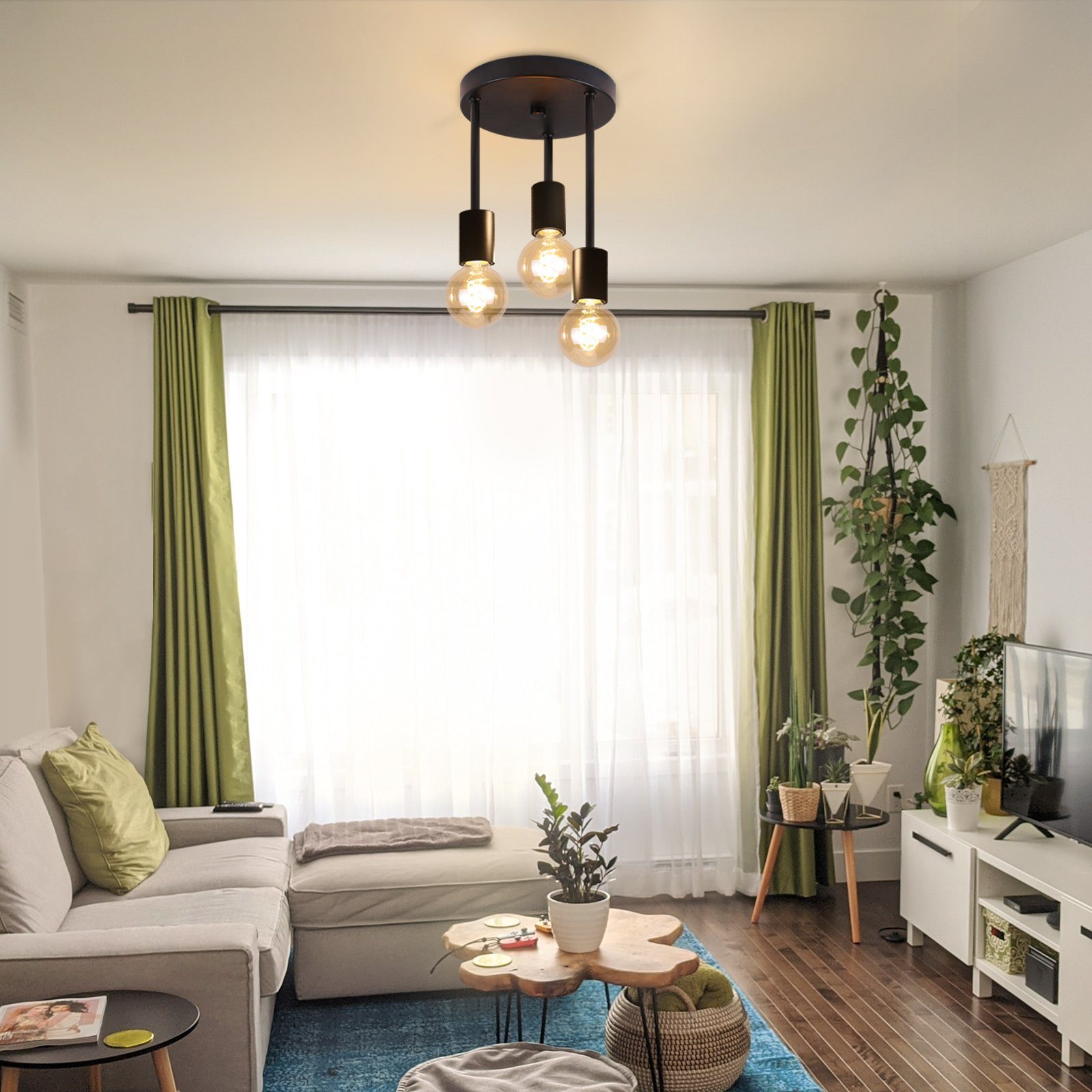 Salon z sofą, roślinami i dużym oknem. Widoczne są trzy wiszące żarówki.