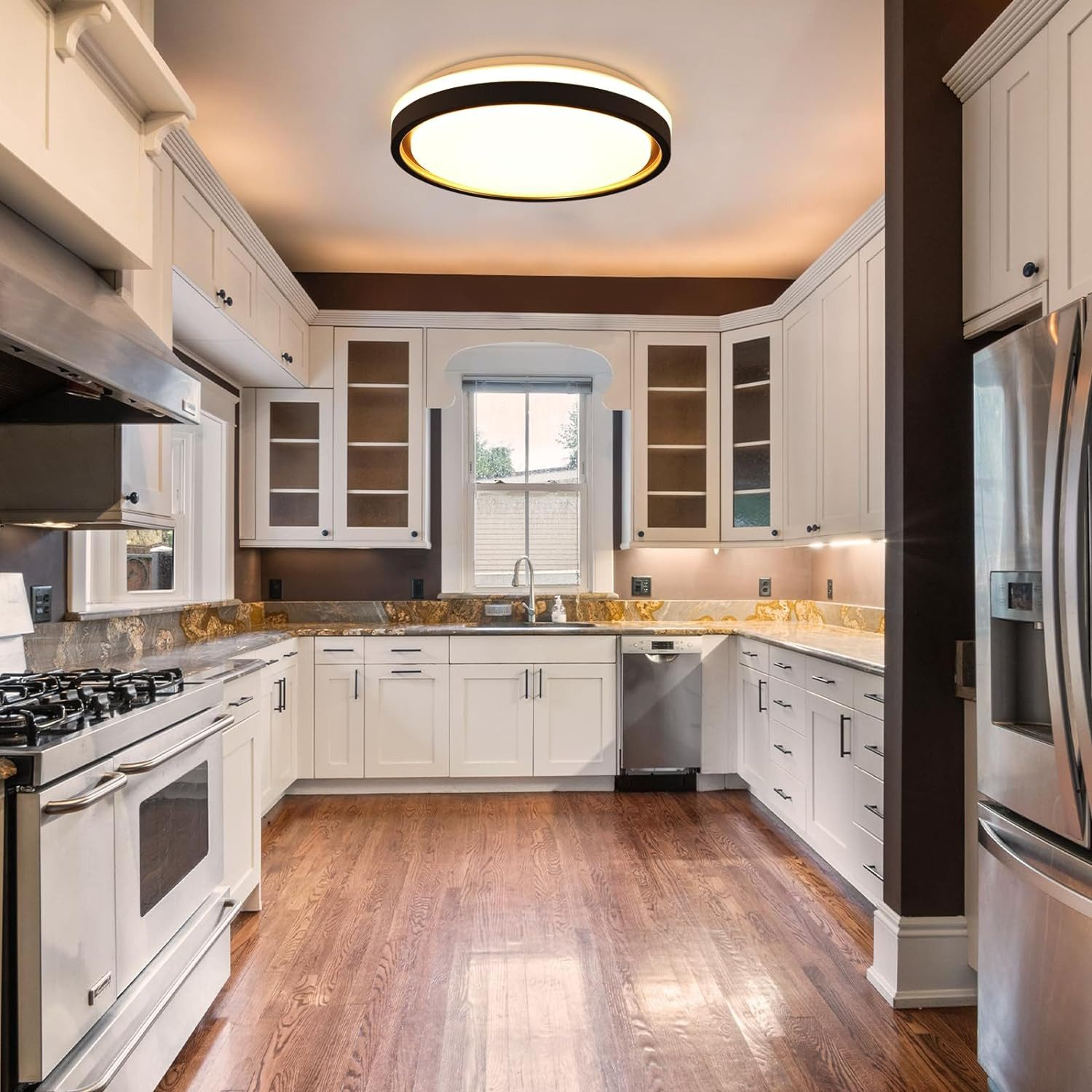 Nowoczesna biała kuchnia z drewnianą podłogą, białymi szafkami i dużym oświetleniem sufitowym.