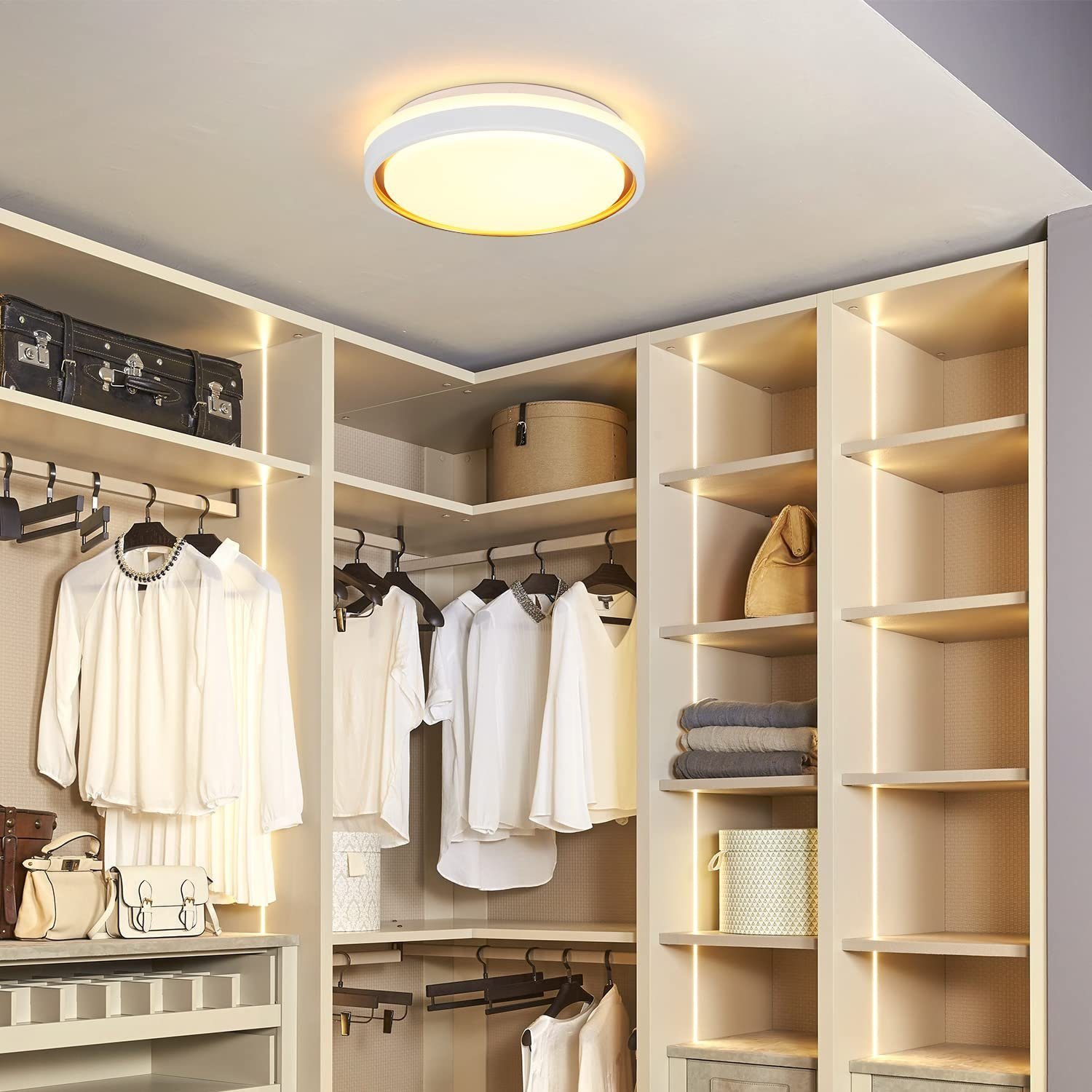 Garderoba z białymi półkami i ubraniami. W środku pokoju znajduje się okrągła lampa sufitowa.