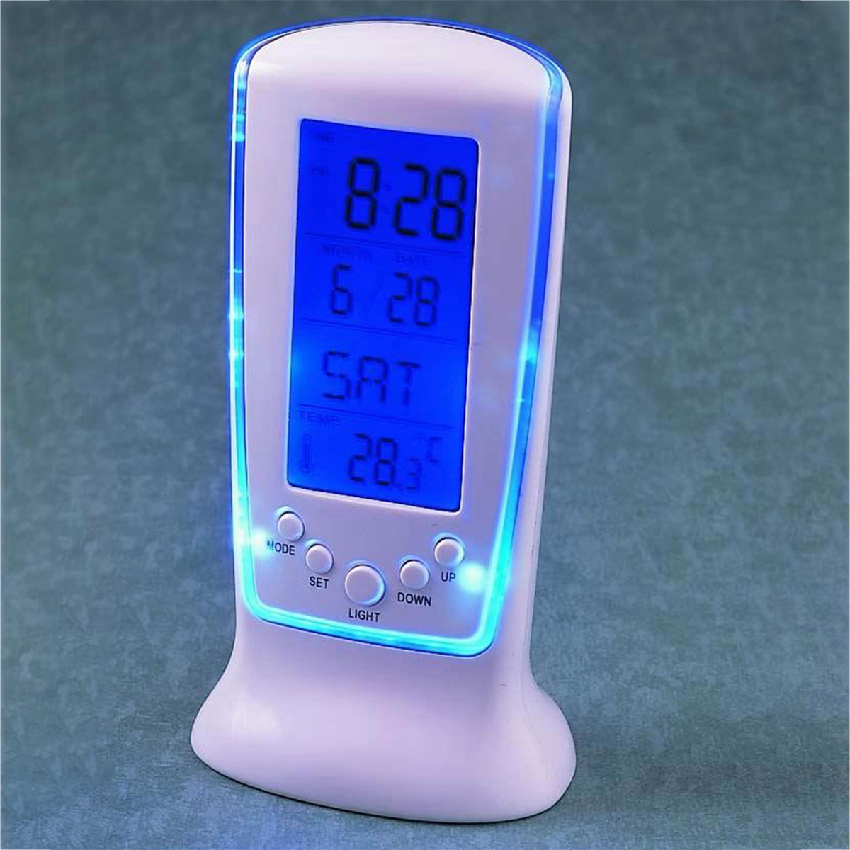 Ein weißer digitaler Wecker. Er zeigt Zeit, Datum und Temperatur in Blau an.