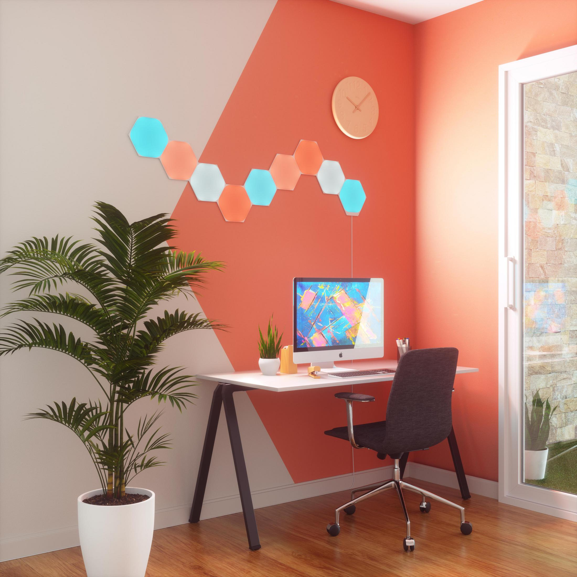 Ein modernes Heimbüro mit Computer, Schreibtisch und Wanddekor mit sechseckigen Lichtern.