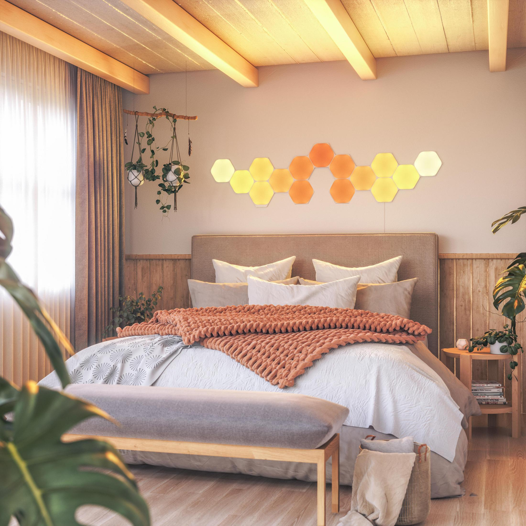Ein Schlafzimmer mit Bett, Hängepflanze und sechseckigen Lichtern an der Wand.