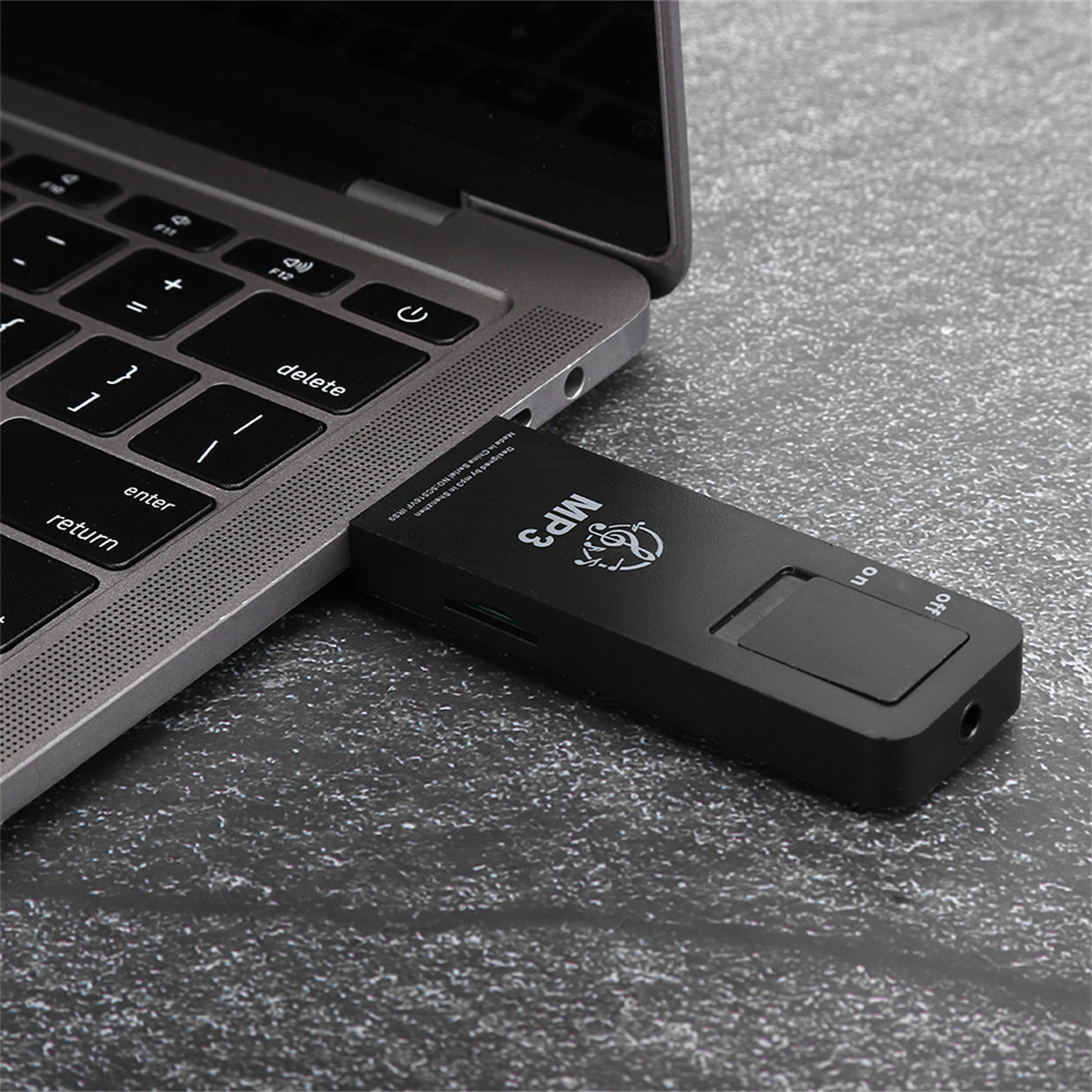 Schwarzer MP3-Player, der an einen Laptop angeschlossen ist. Der MP3-Player liegt auf dunkler Oberfläche.