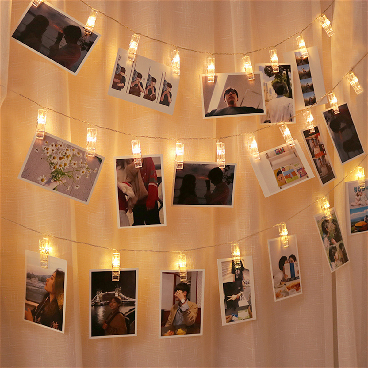 Lichterkette mit angebrachten Bildern. Die Bilder sind Fotos, und der Hintergrund ist ein heller Vorhang.