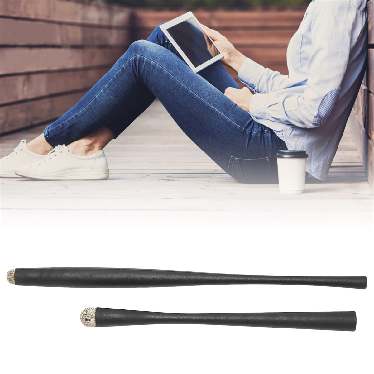 Eine Person liest ein Tablet und zwei schwarze Stifte auf einer Holzoberfläche.