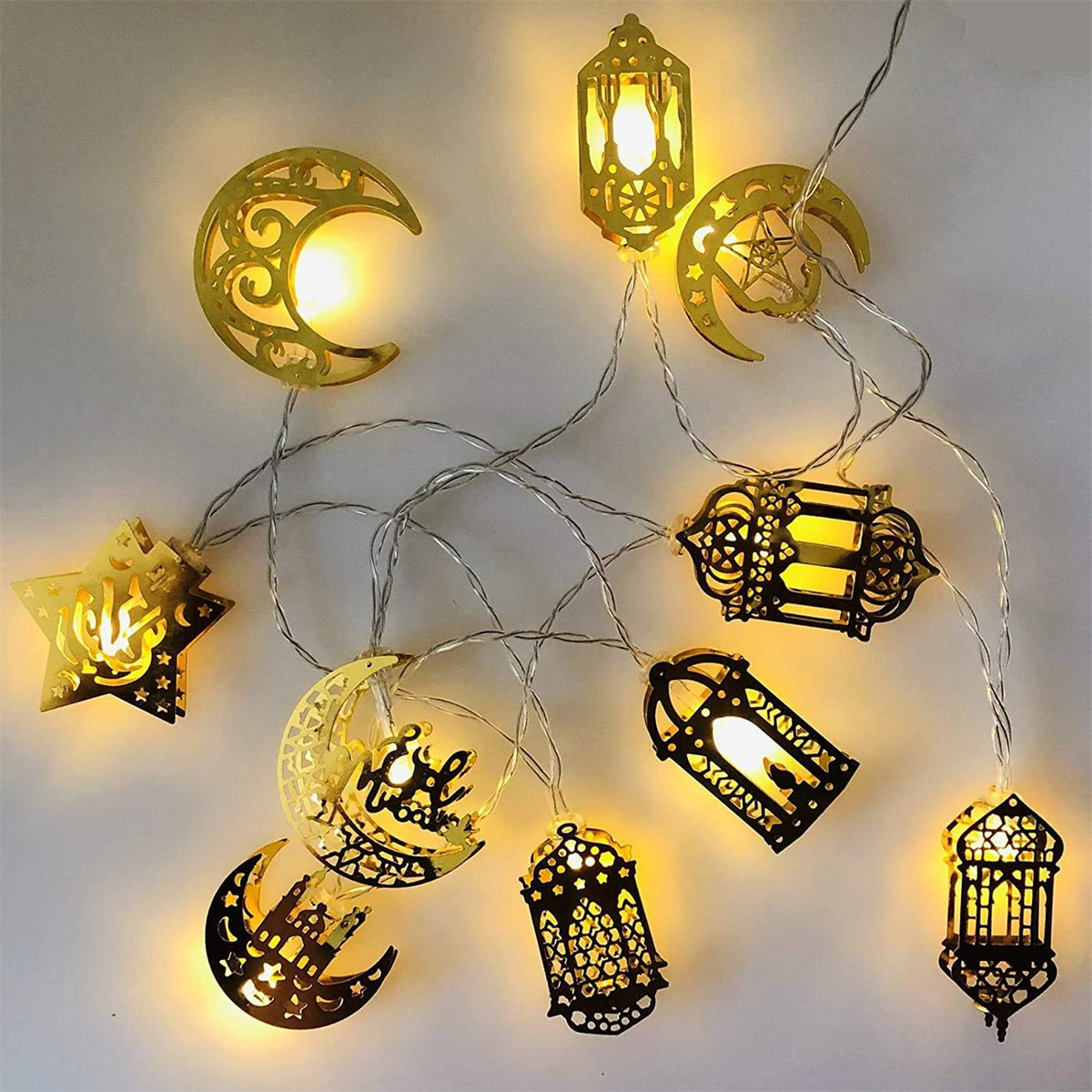 Lichterkette mit verschiedenen goldfarbenen Ramadan-Dekorationen, beleuchtet.
